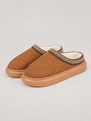 Brown suede platform slippers feature a closed-toe mule silhouette, plush faux fur lining, decorative stitched trim, and thick rubber soles.