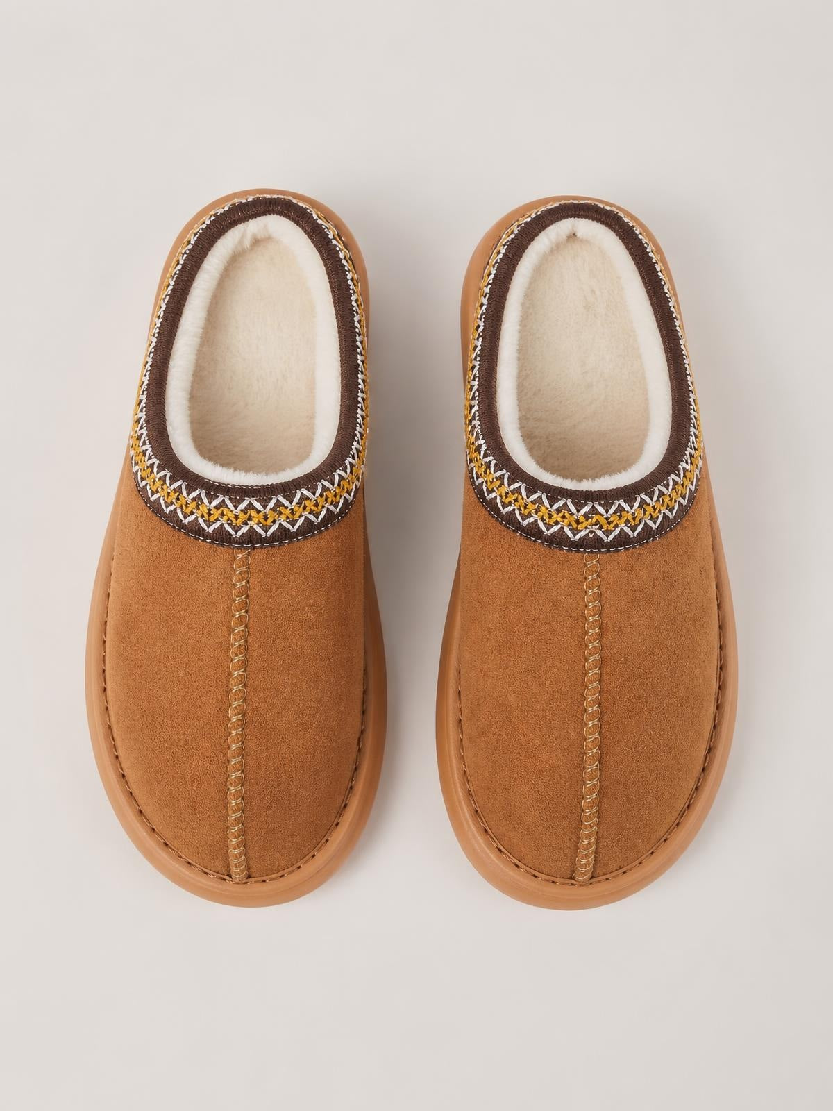 Tan suede platform slippers with soft faux fur lining, rounded closed toes, decorative multicolor stitching, and sturdy rubber soles.