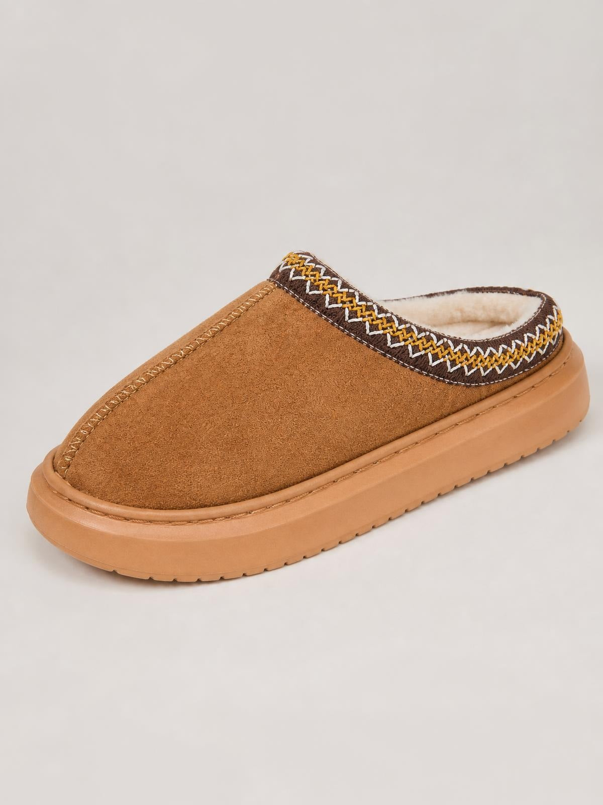 Tan suede platform slippers feature a slip-on mule silhouette, faux fur lining, decorative embroidered trim, and a chunky rubber sole.