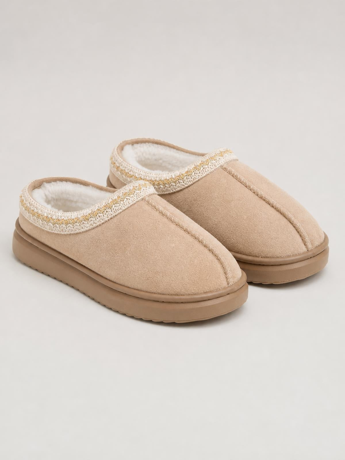 Tan suede platform slippers feature rounded closed toes, soft faux fur lining, decorative stitched trim, and thick rubber soles with a flat profile.