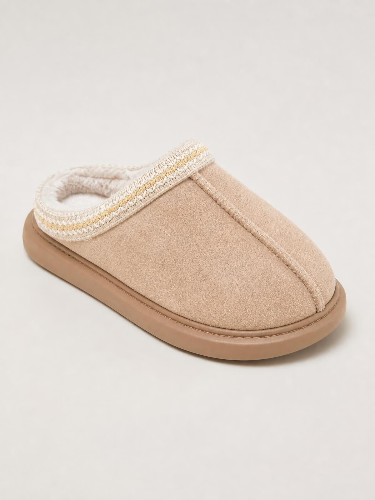 Beige suede platform slipper with a closed toe, plush faux fur lining, decorative stitched trim, and a thick rubber sole.