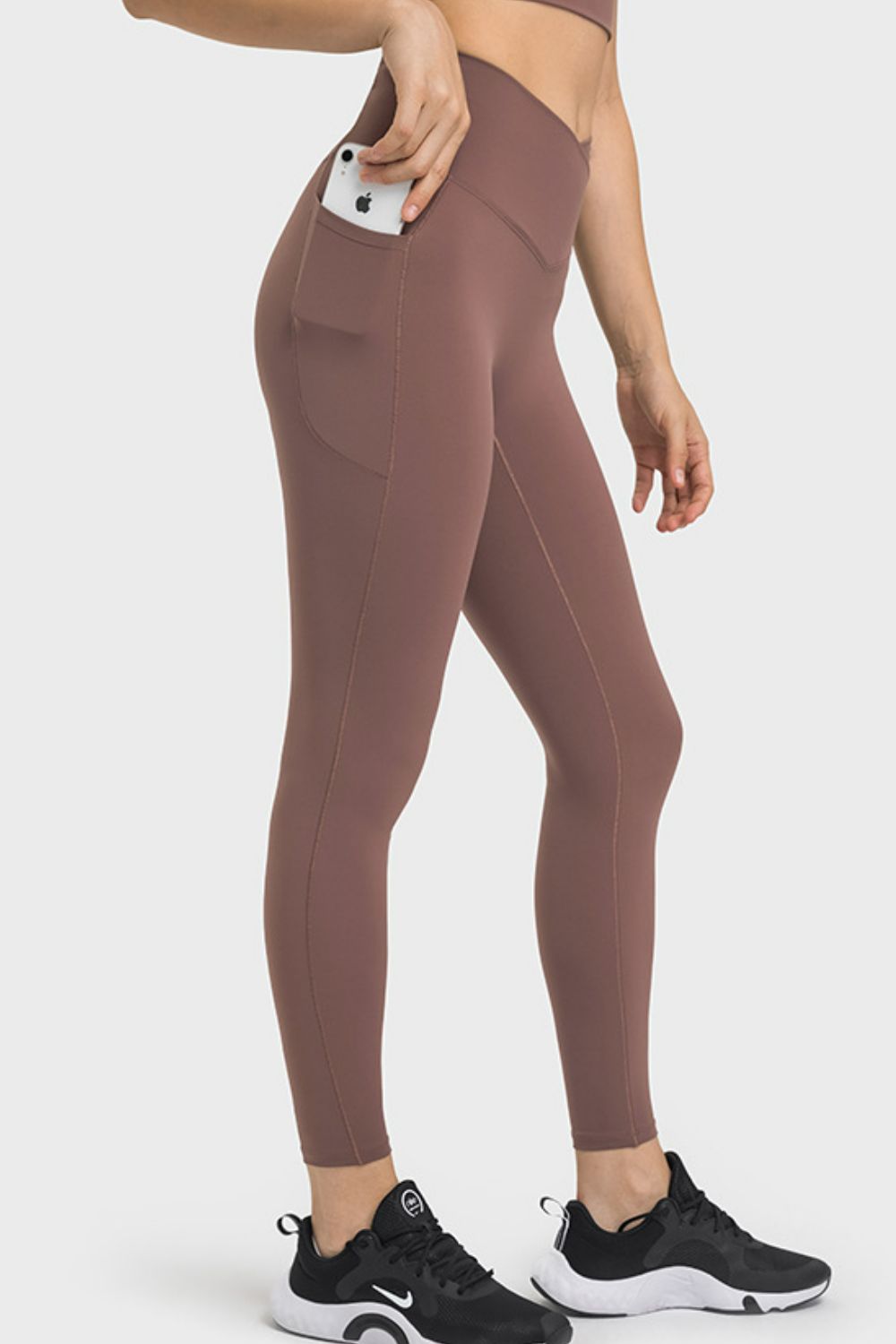Model wearing mauve V-waist yoga leggings with a side phone pocket, stretch fit, and contour seams in a sleek, ankle-length silhouette.