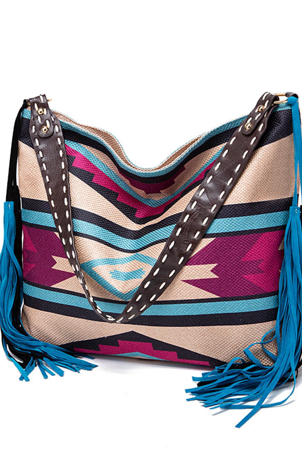 Oversize geometric canvas tote bag with colorful striped and chevron panels, wide black stitched straps, and long blue fringe trim.