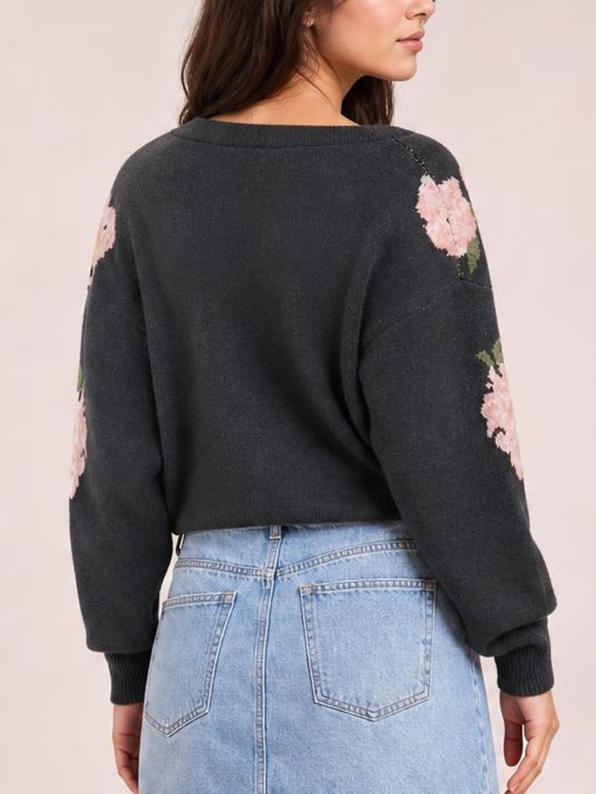 Back view of a model wearing a charcoal floral boat neck long sleeve sweater with a relaxed cropped silhouette, ribbed neckline, cuffs, and hem.