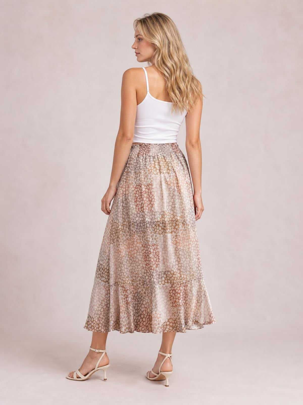 Model shown from behind in a flowing floral maxi skirt with a soft brown and blush pattern, gathered waistband, and relaxed A-line silhouette.