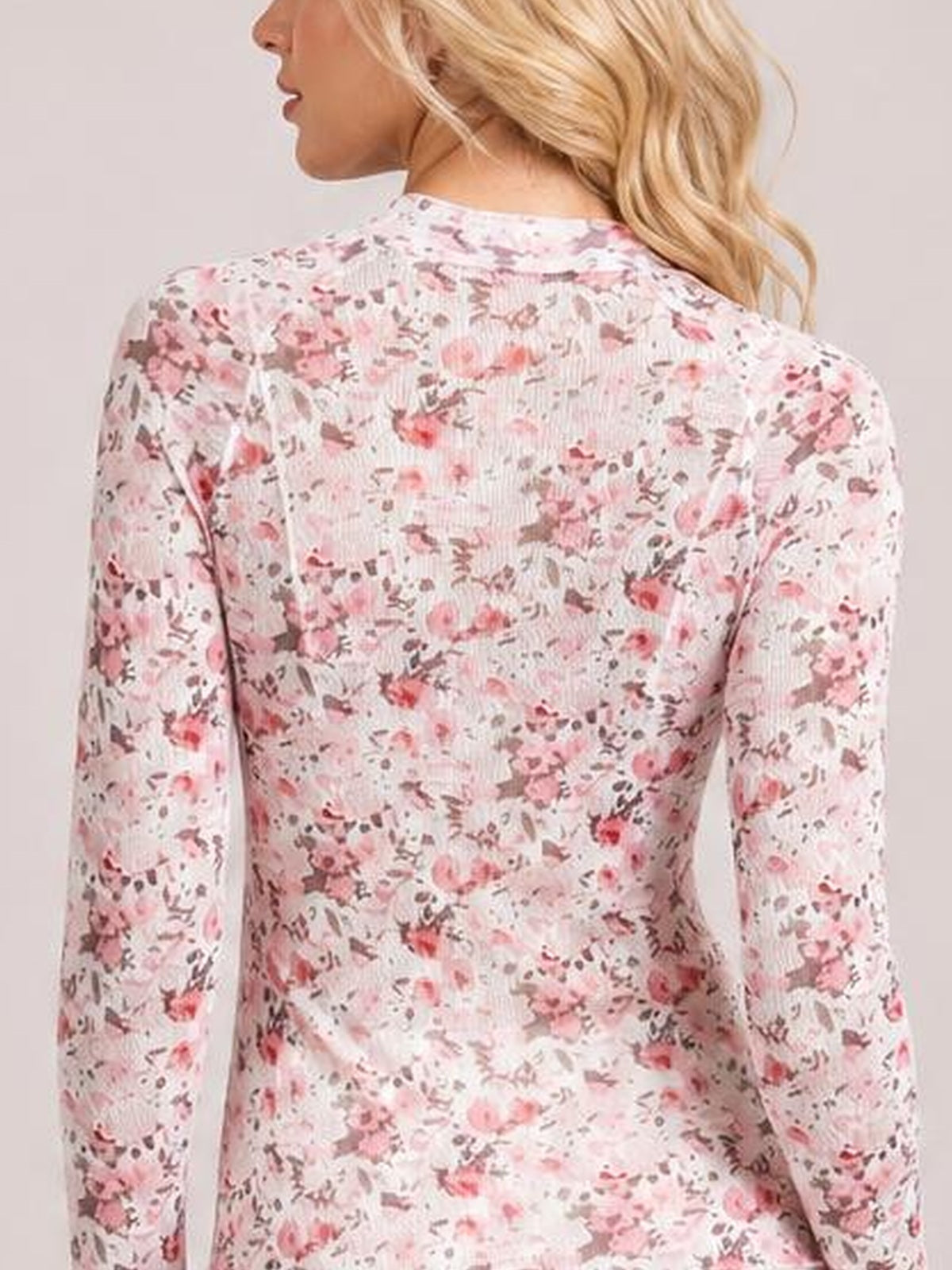 Model shown from the back wearing a light pink floral mock neck long sleeve top with a close-fitting silhouette and stretch fabric.