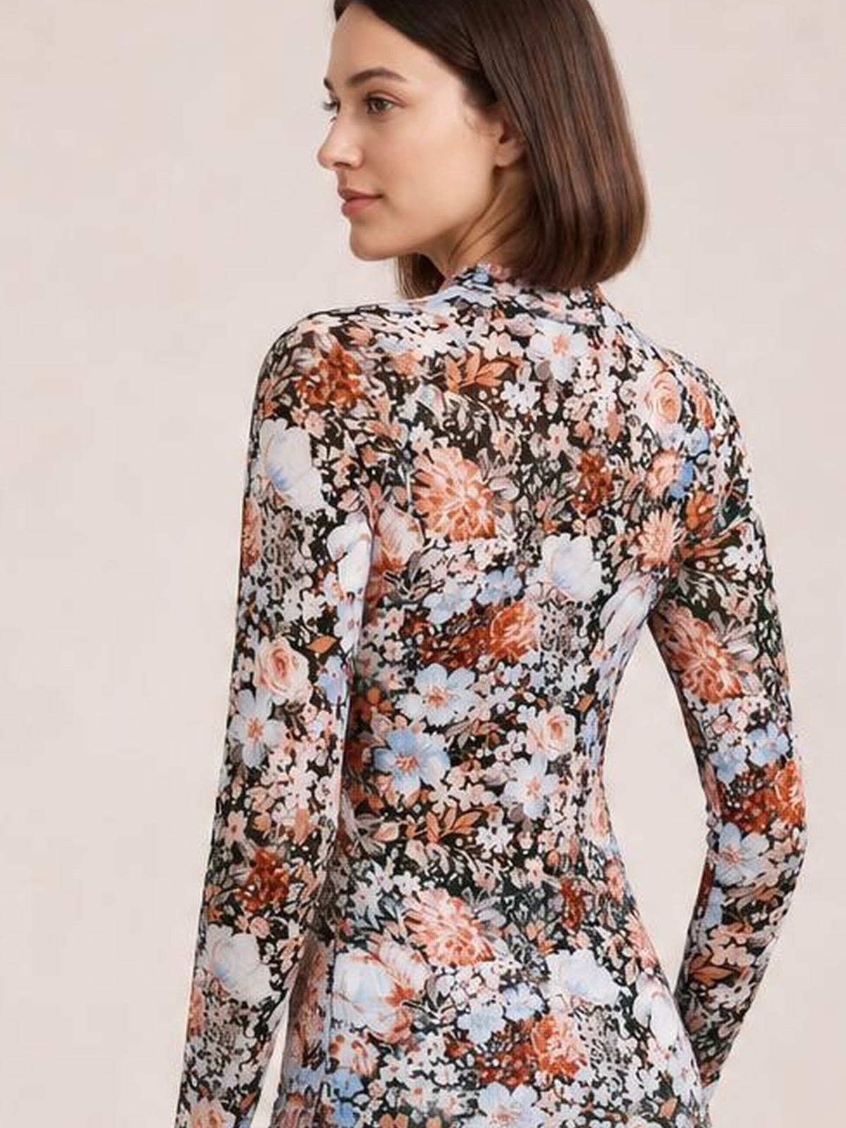 Model turned away in a fitted floral mock neck long sleeve top with a multicolor flower print and smooth, slightly stretchy silhouette.