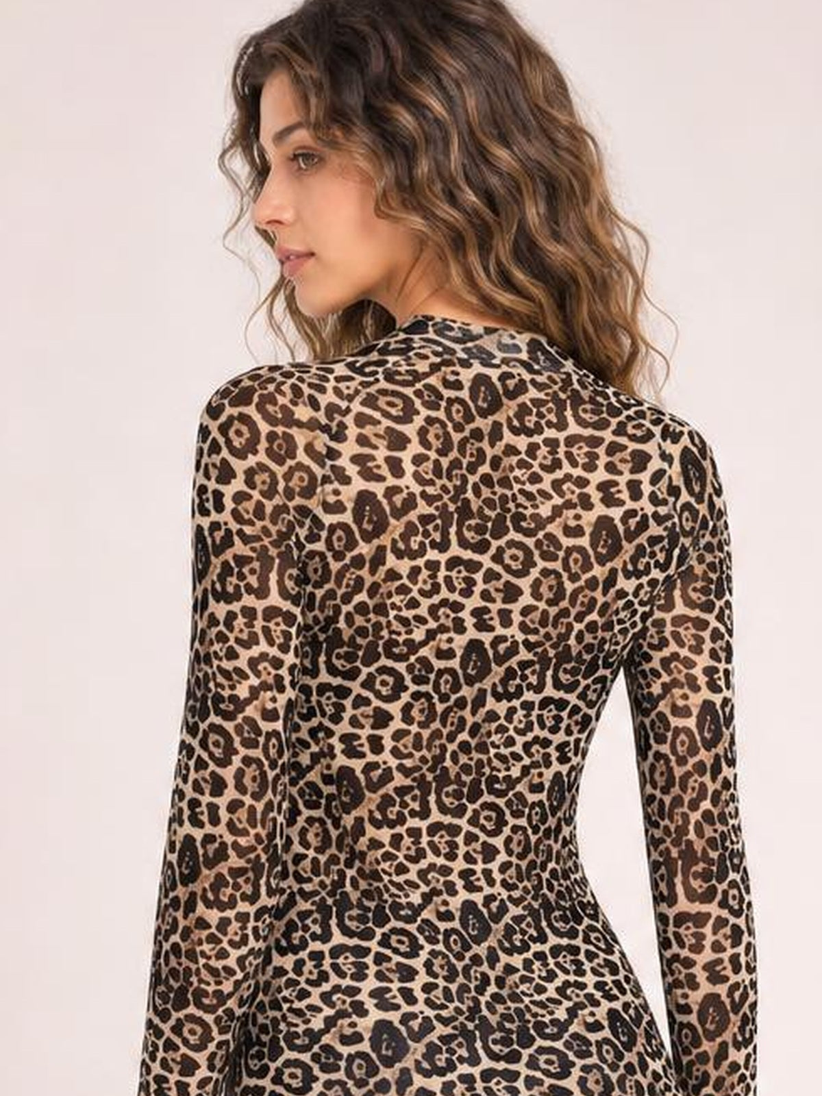 A model looks over her shoulder wearing a fitted leopard-print mock neck top with long sleeves and a smooth, slightly stretchy silhouette.