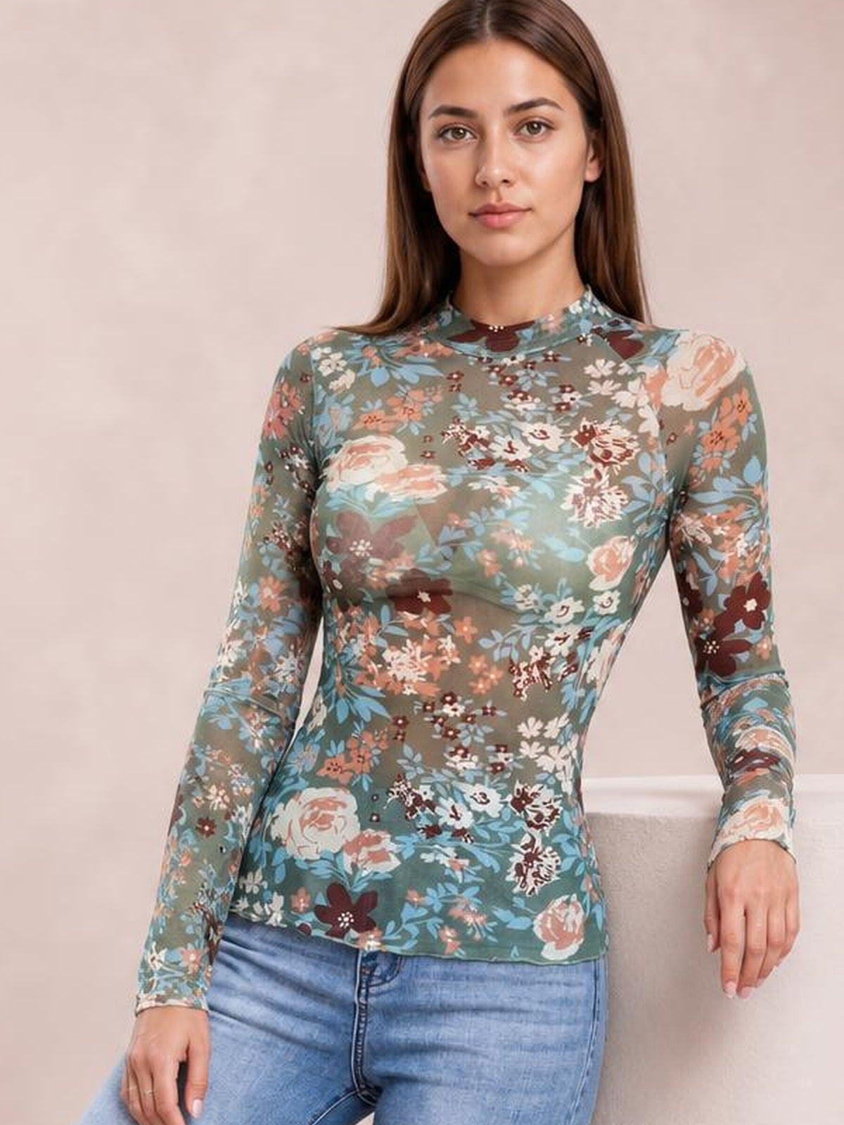 Model wears a blue-gray floral mock neck long sleeve top with a fitted silhouette, crew neckline, and full-length sleeves while standing facing forward.