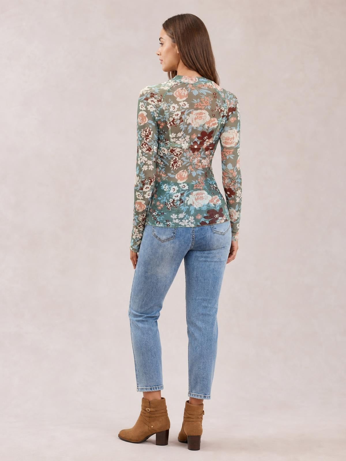 Model shown from the back wearing a fitted floral mock neck long sleeve top in muted teal, pink, cream, and brown with a smooth hem.