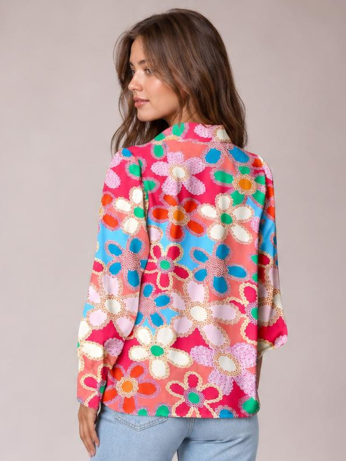 Model looks over her shoulder wearing a colorful floral print collared shirt with long lantern sleeves, buttoned front, and a relaxed regular-length silhouette.