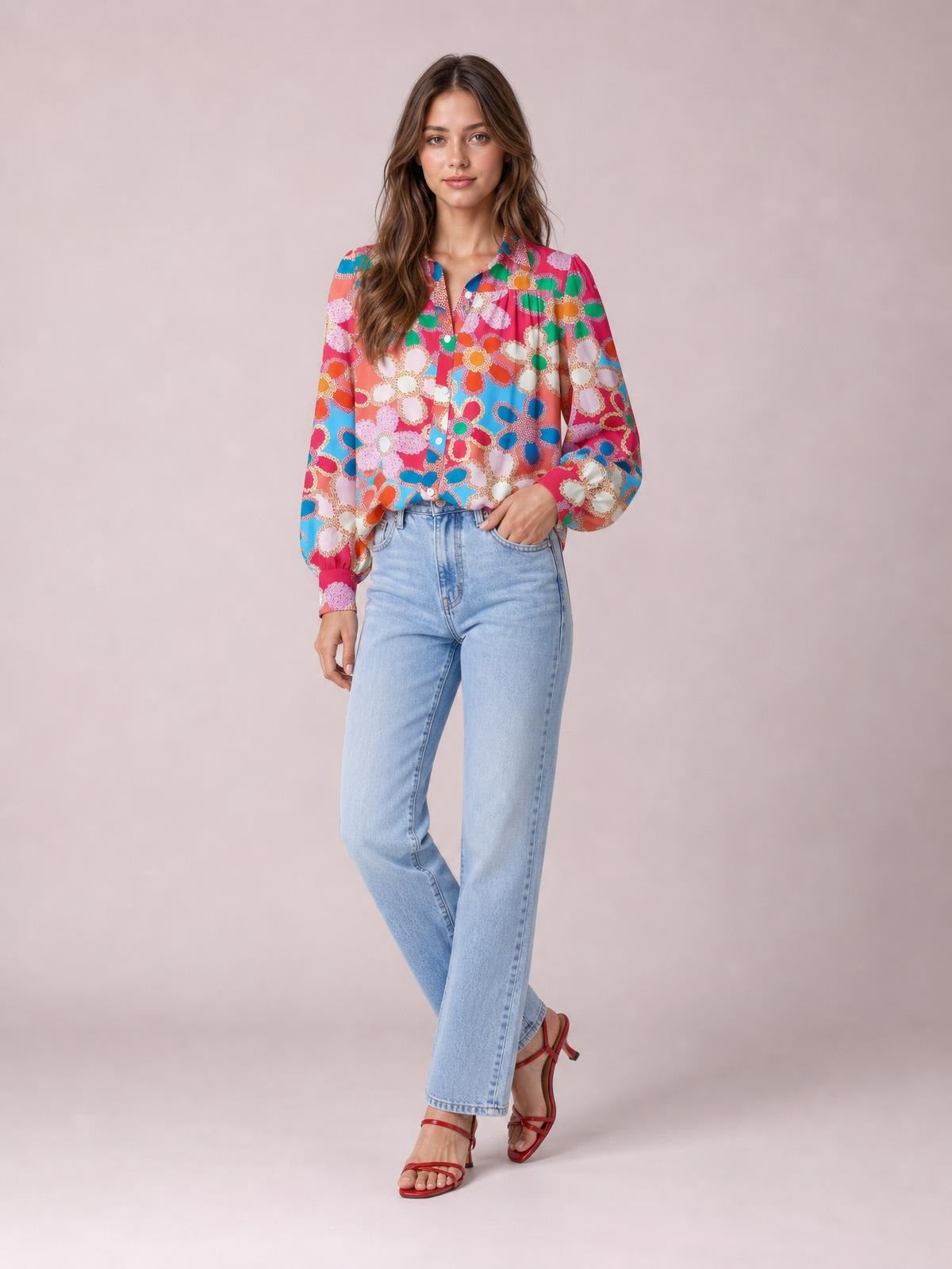 Model poses in a colorful floral print shirt with a collared neckline, button front, regular length, and voluminous lantern sleeves with gathered cuffs.