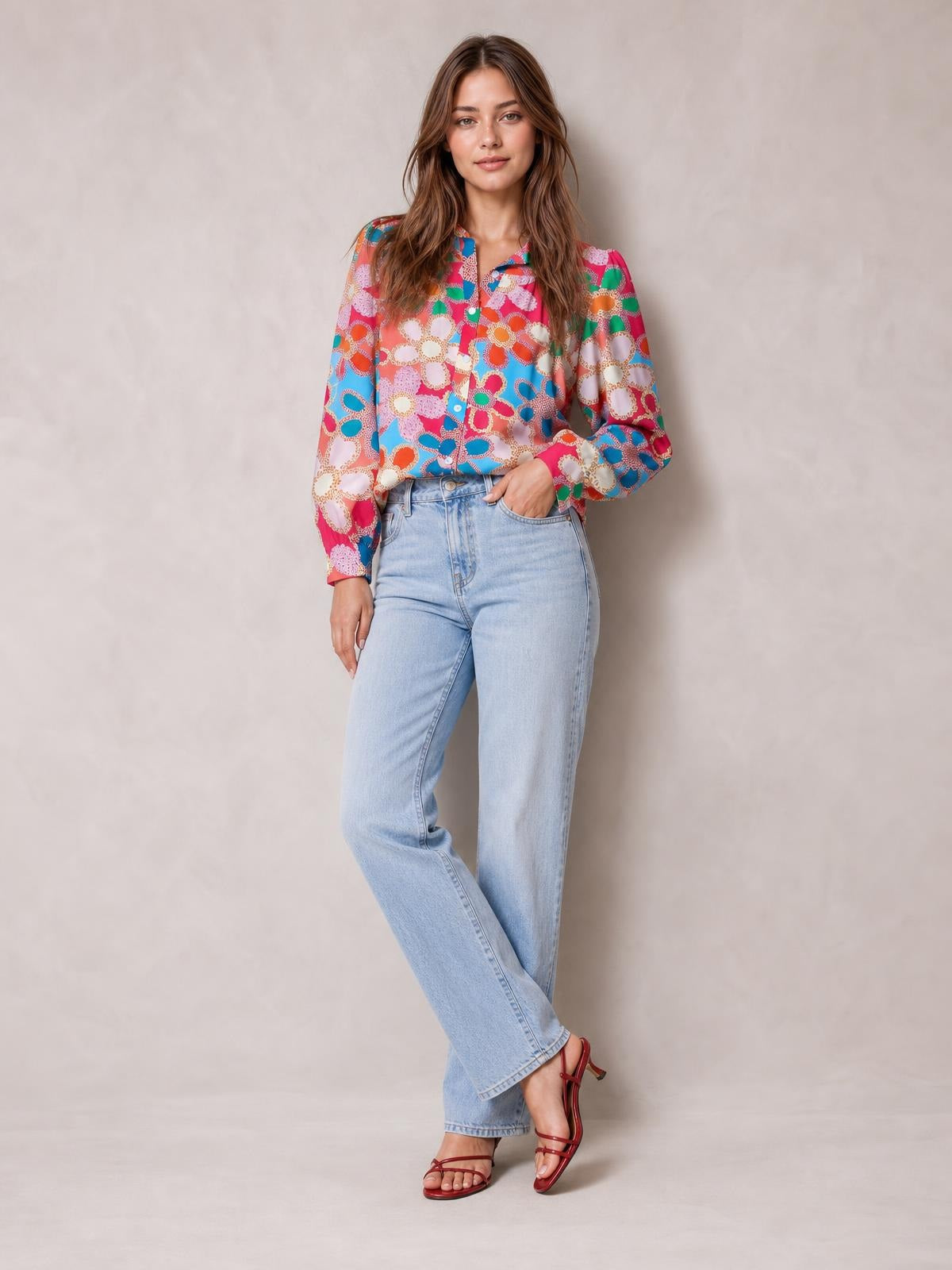 A model poses in a colorful floral print shirt with a collared neckline, button front, regular length, and long lantern sleeves.