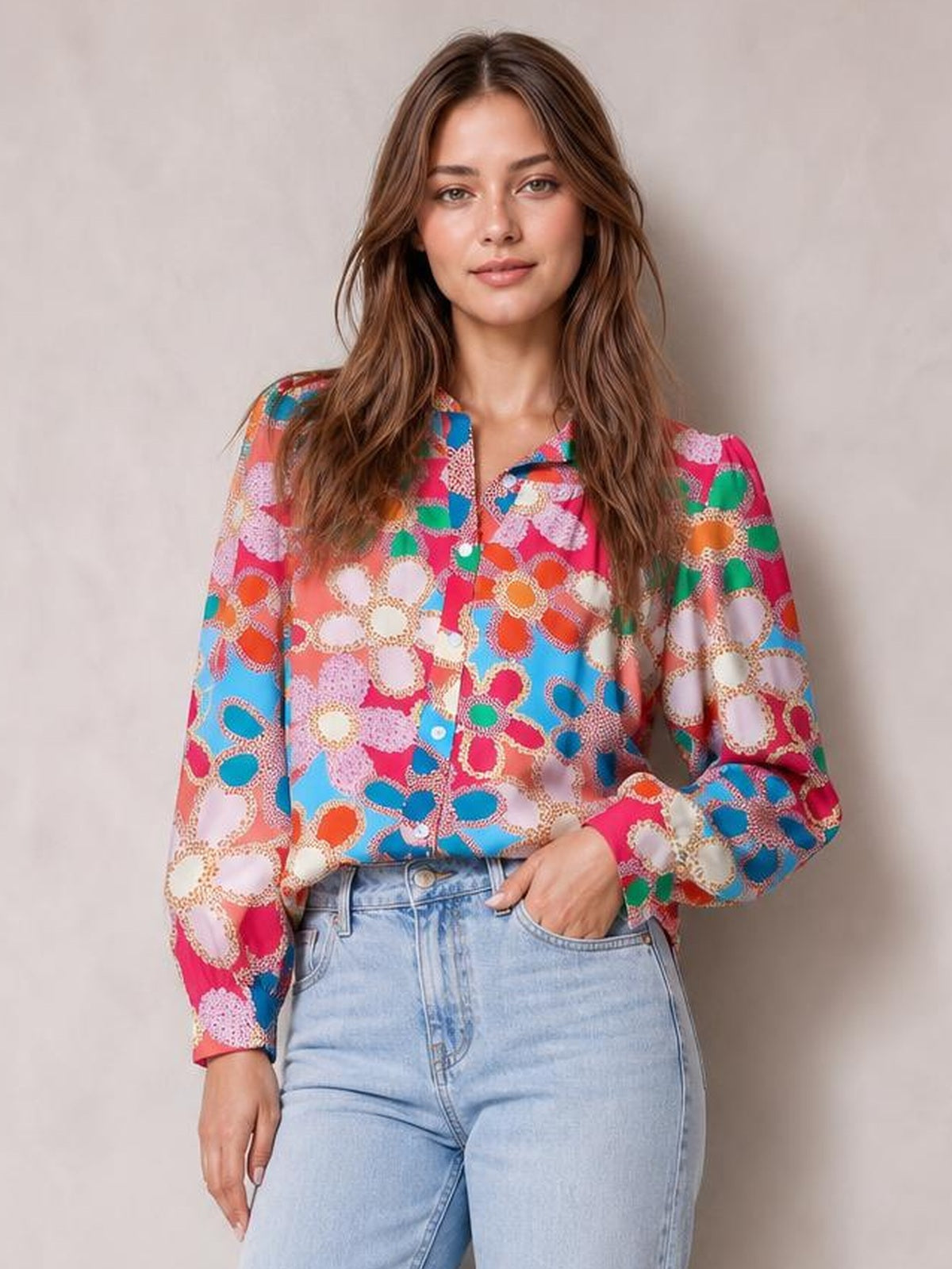 Model wearing a colorful floral print shirt with a collared neckline, button front, regular length, and long lantern sleeves, posing with one hand in a jeans pocket.