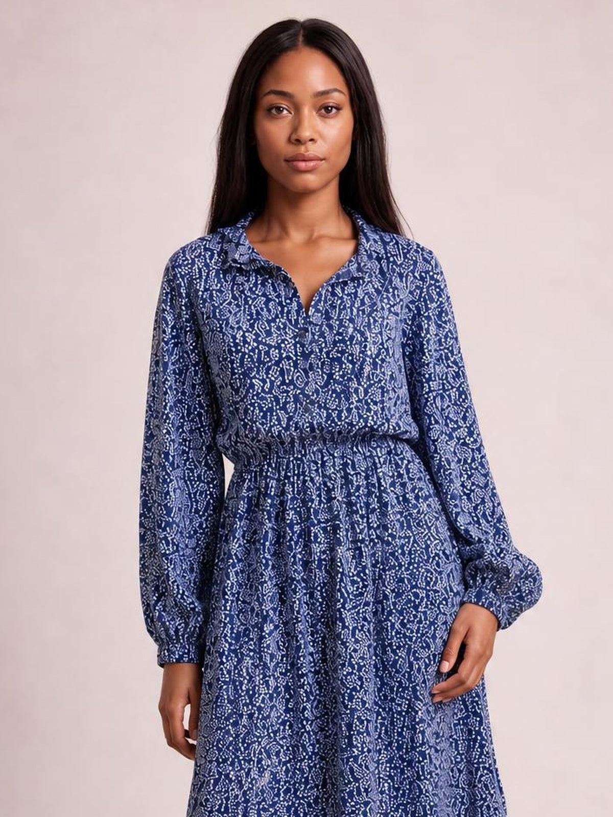 A model stands wearing a navy floral print long-sleeve midi dress with a collared neckline, smocked waist, and gathered full skirt.