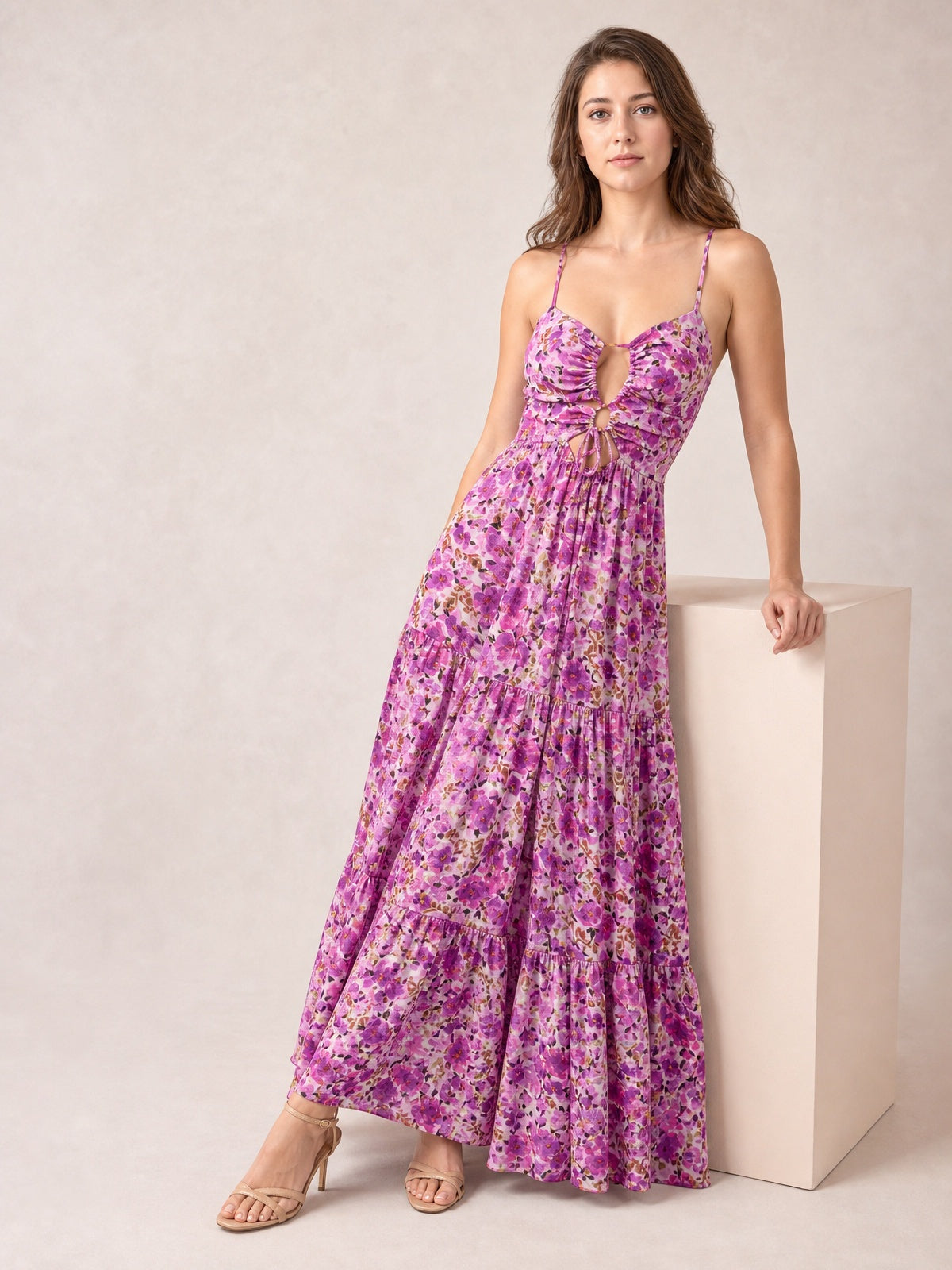 Model poses in a purple floral print tie-front maxi dress with slender straps, cutout bodice, gathered waist, and flowing tiered skirt.