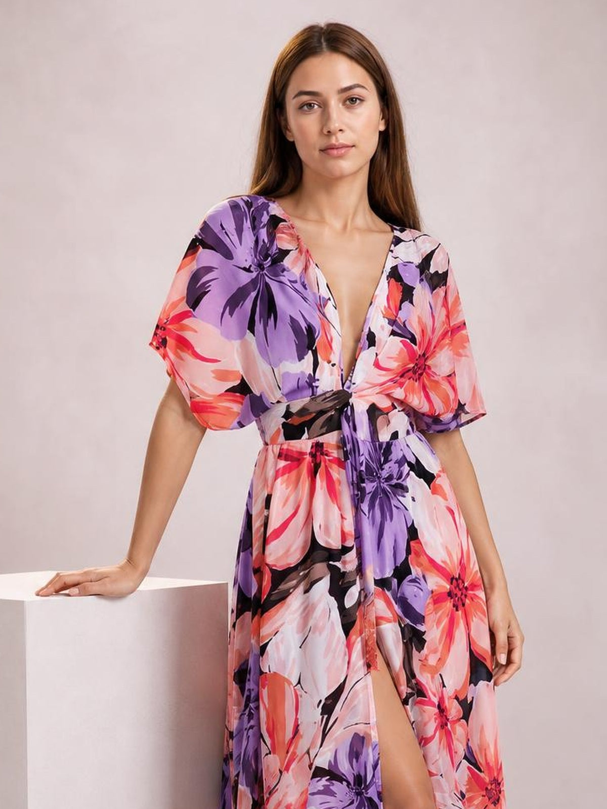 Model in a colorful floral print maxi dress with a deep V-neck, short sleeves, cinched waist, flowing silhouette, and high front slit.