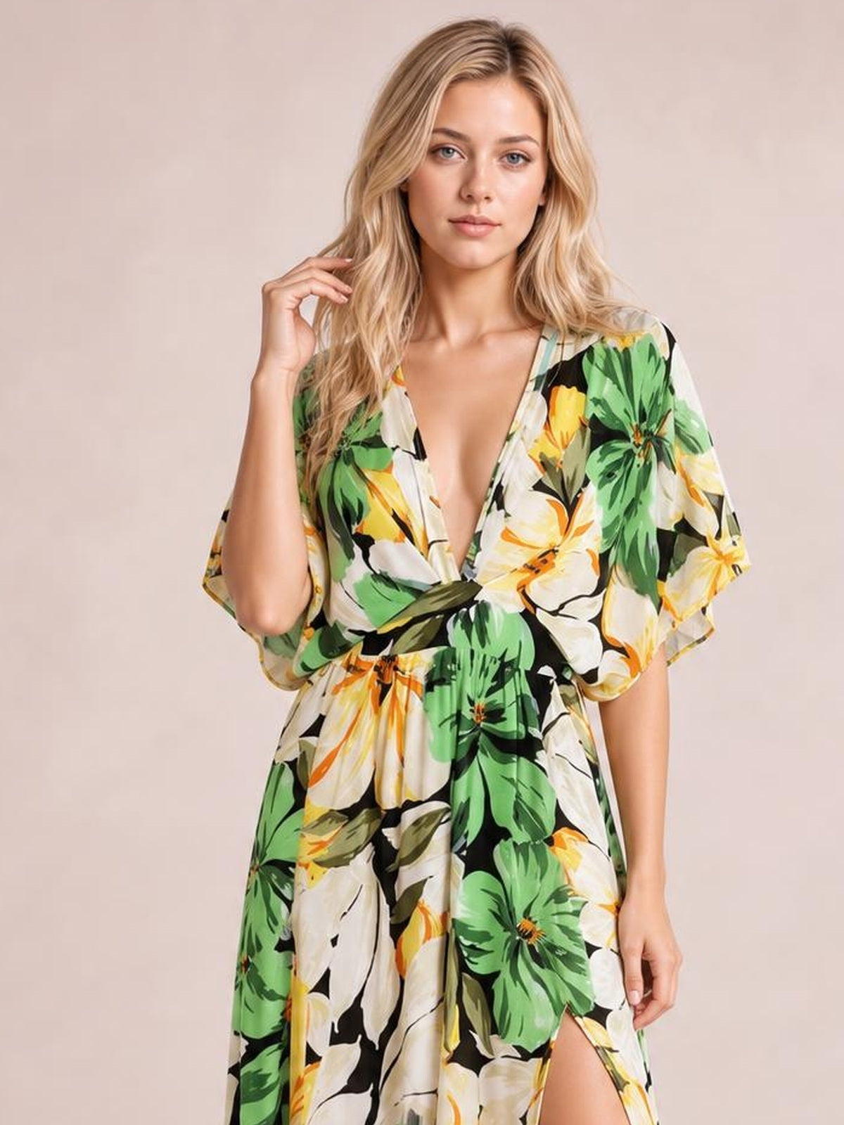A model poses in a green, yellow, white, and black floral print maxi dress with a deep V-neck, twisted waist, flowing silhouette, and high side slit.