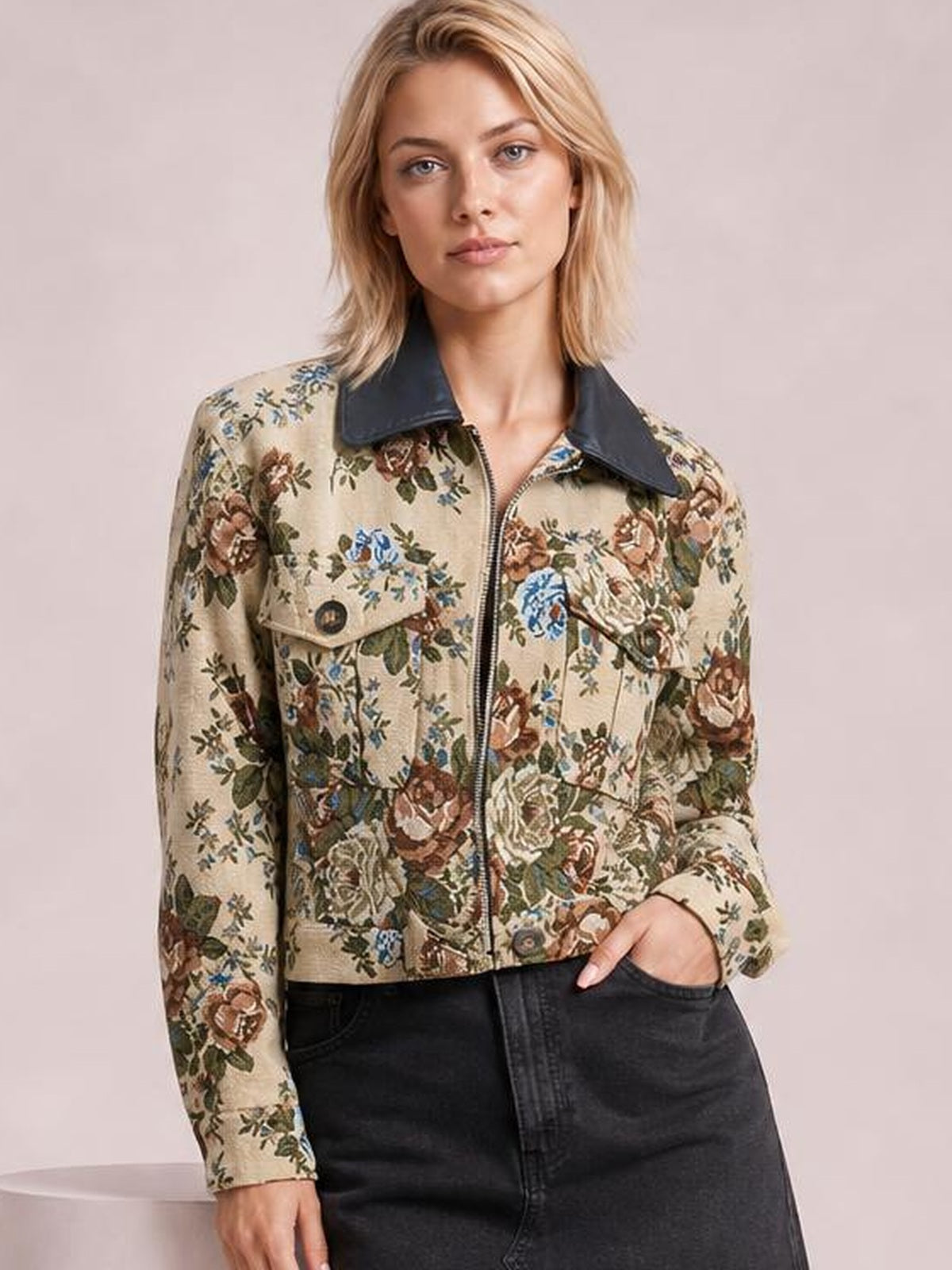 Model wearing a beige floral print zip-up jacket with a dark contrast collar, buttoned chest pockets, long sleeves, and a cropped silhouette.