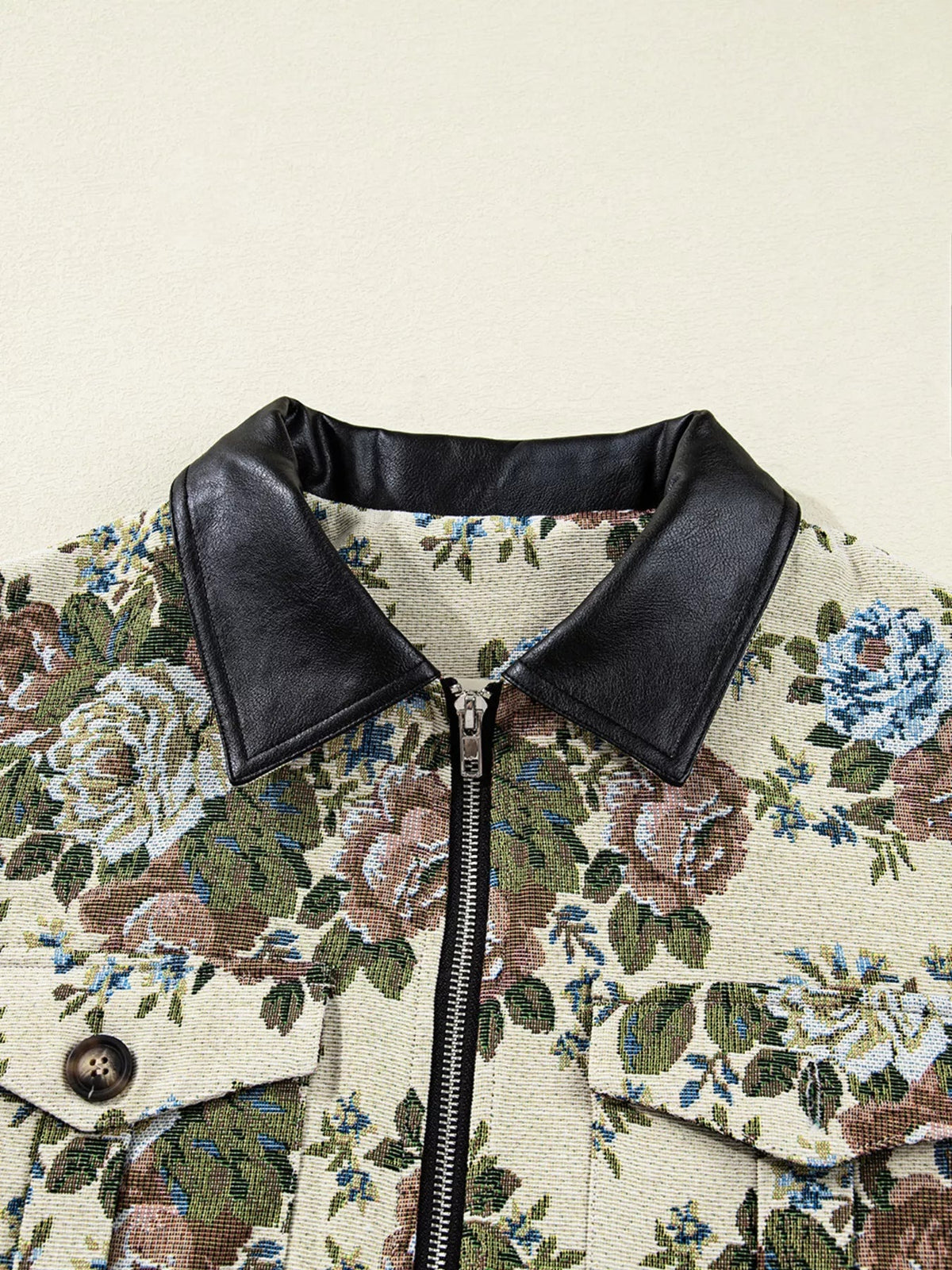 Close-up of a floral print jacket featuring a black contrast collar, central zip front, button detail, and visible pocket construction.