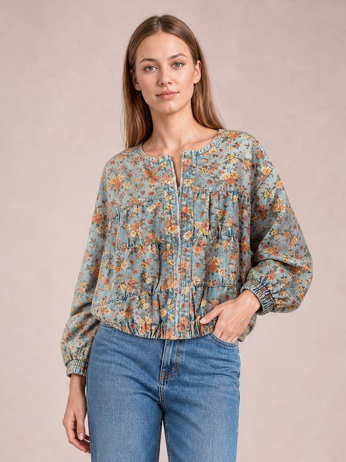 Model poses with one hand in her jeans pocket, wearing a blue floral-print cropped denim jacket with a zip front, long sleeves, and elastic cuffs.