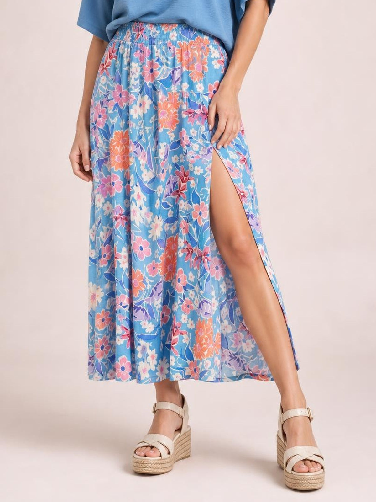 Model wears a flowy blue floral printed high waist split skirt with a flattering A-line silhouette, elastic waistband, and thigh-high side slit.