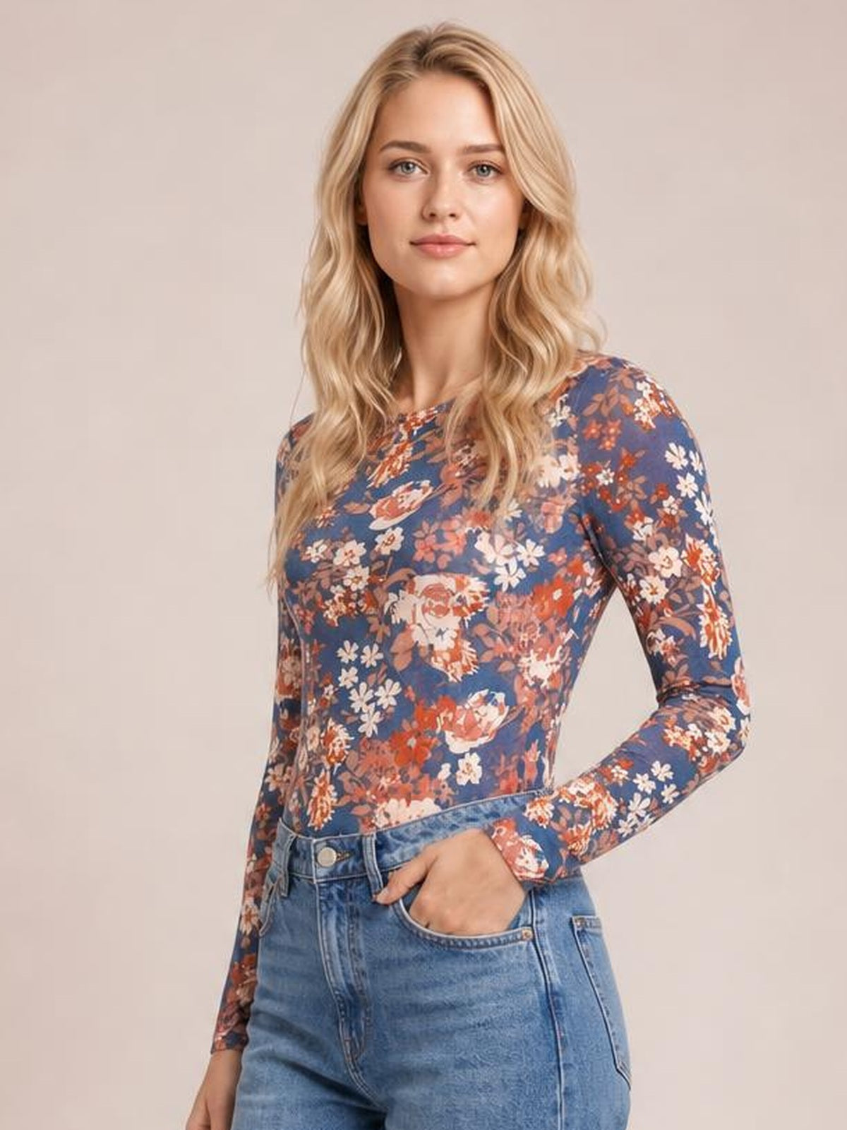 Model wearing a fitted navy floral round neck long sleeve T-shirt with an allover multicolor flower print, posed with one hand in her jeans pocket.