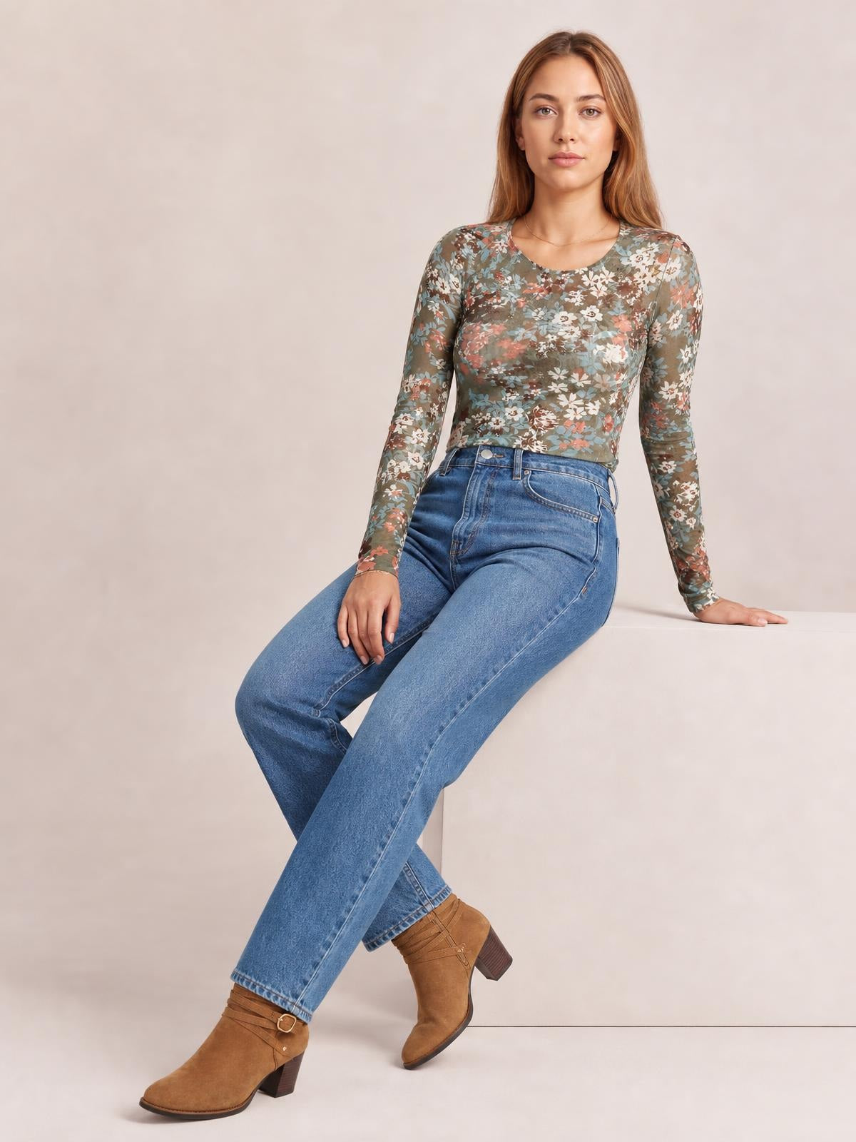 Model seated in a floral round neck long sleeve T-shirt with a fitted silhouette, muted green base, and multicolor flower print.