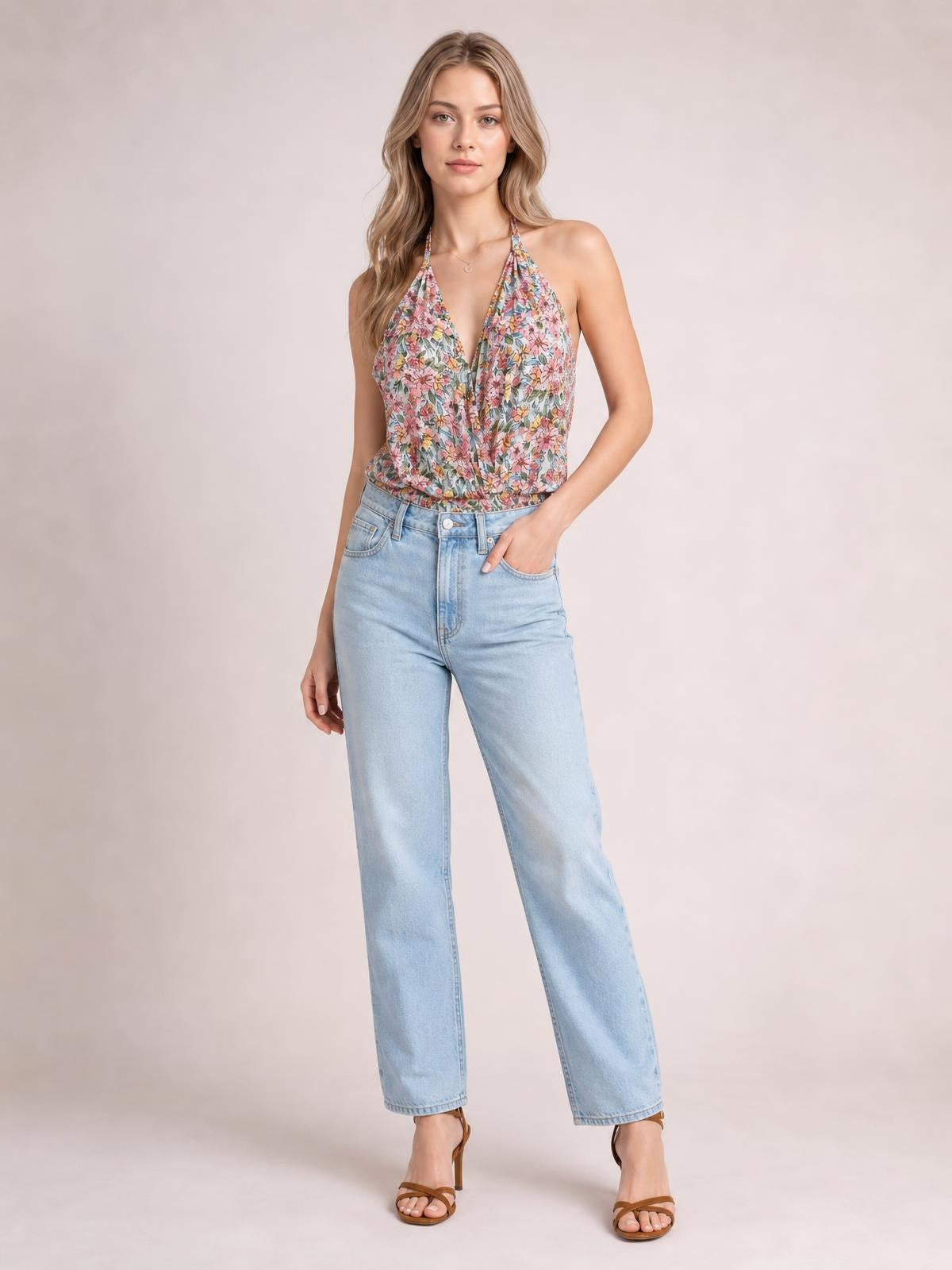 Model poses in a colorful floral surplice neck top with sleeveless halter straps, a crossover front, and a relaxed regular-length silhouette.