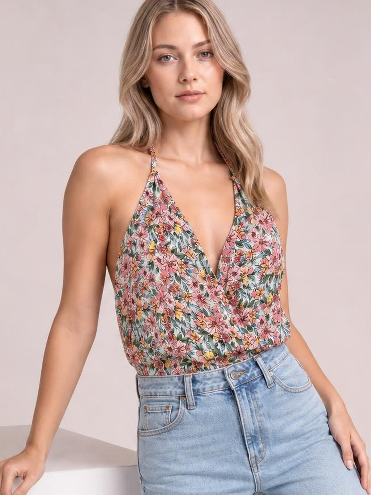Model wears a multicolor floral surplice neck cami with thin straps, sleeveless construction, and a relaxed regular-length silhouette tucked into jeans.