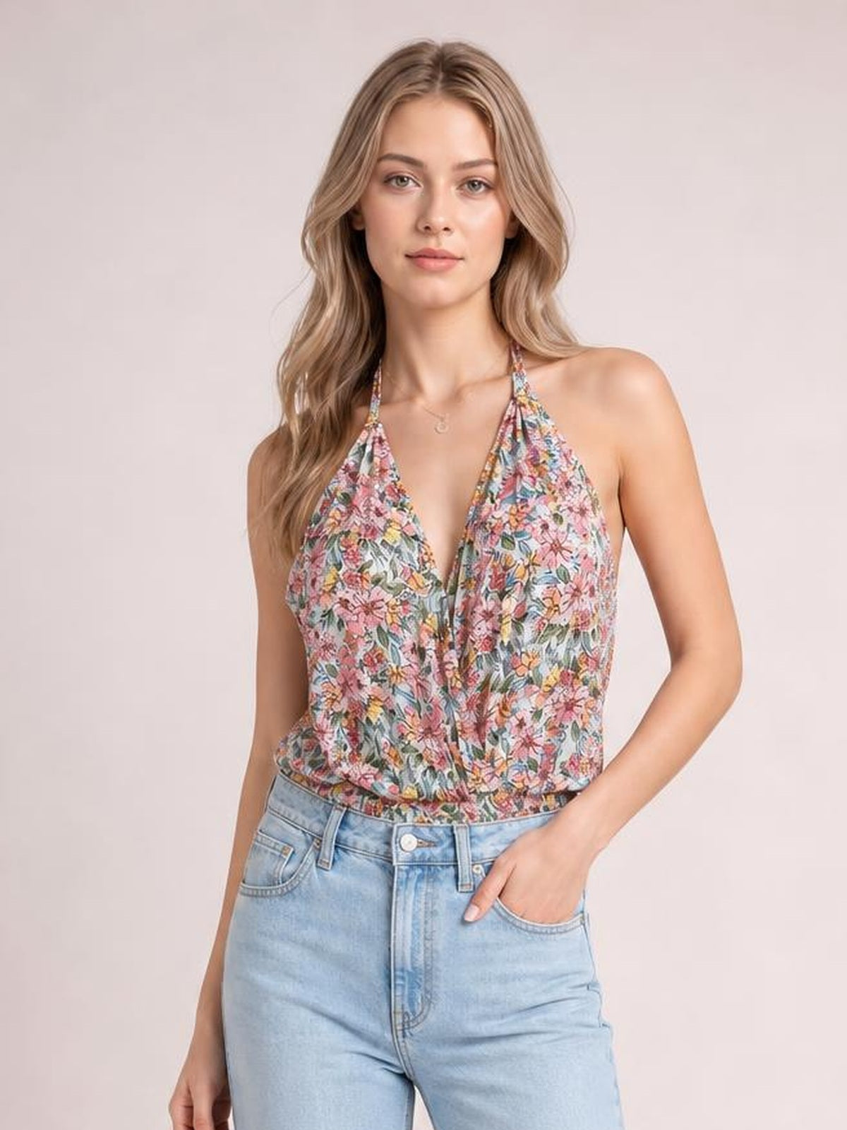 A model wears a multicolor floral surplice neck top with a sleeveless halter silhouette, deep V neckline, and fitted regular-length construction.