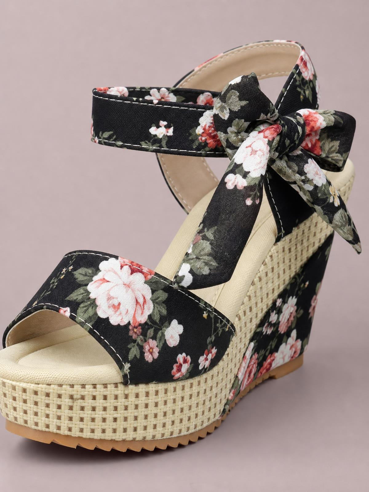 Black floral tied high heel sandals with open toes, wide straps, bow ankle ties, and a tall woven espadrille platform wedge.