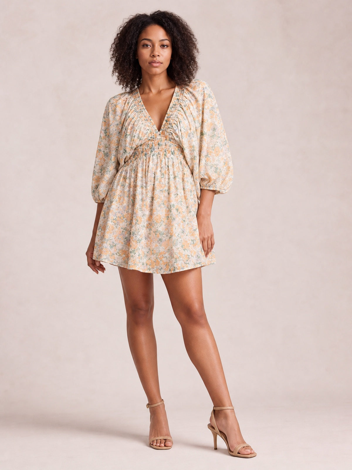 Model poses in a floral V-neck mini dress with a softly gathered waist, ruched detailing, voluminous balloon sleeves, and a gently flared silhouette.