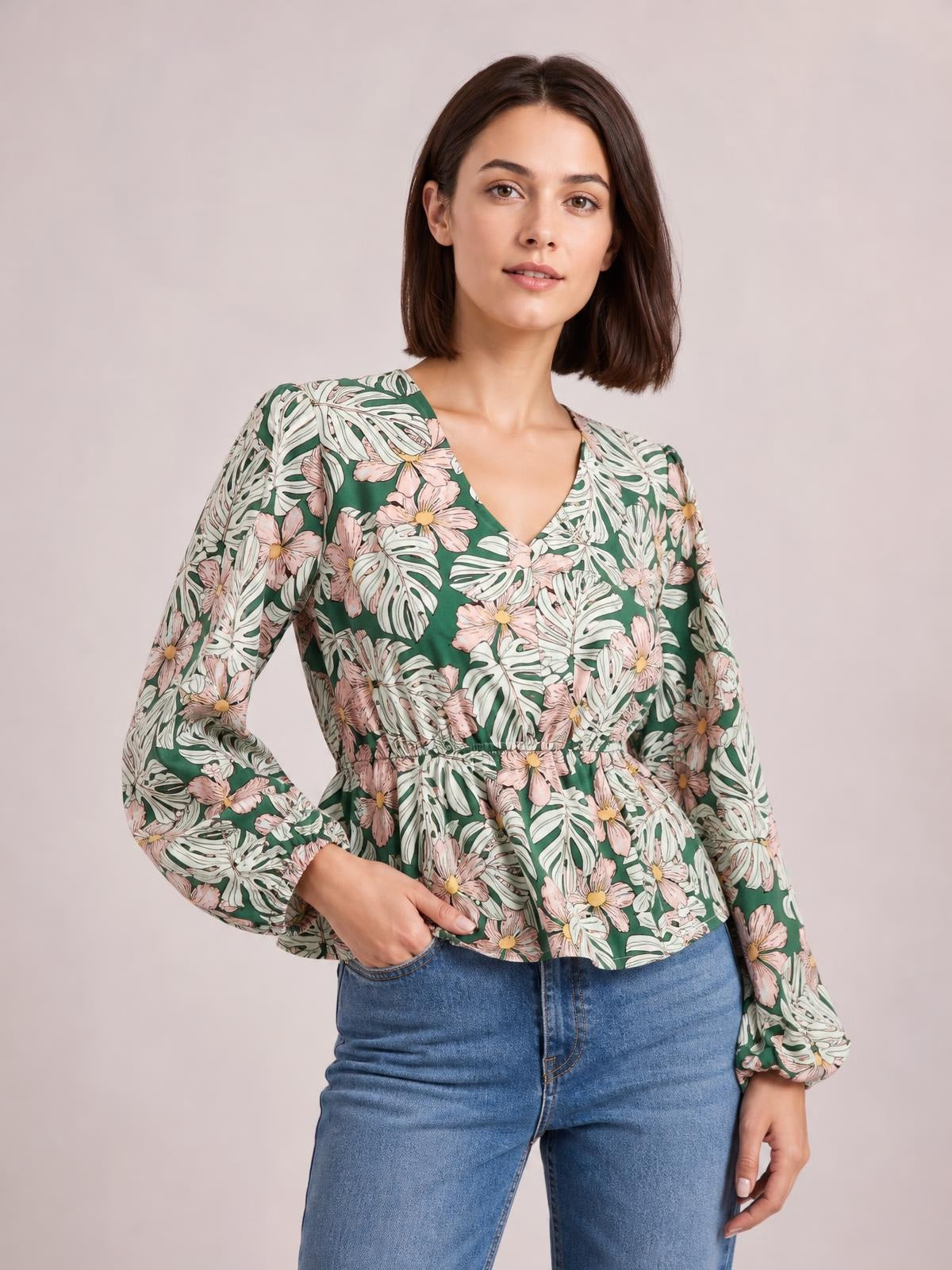 Model poses in a green floral V-neck peplum blouse with a fitted waist, flared hem, and voluminous balloon sleeves.