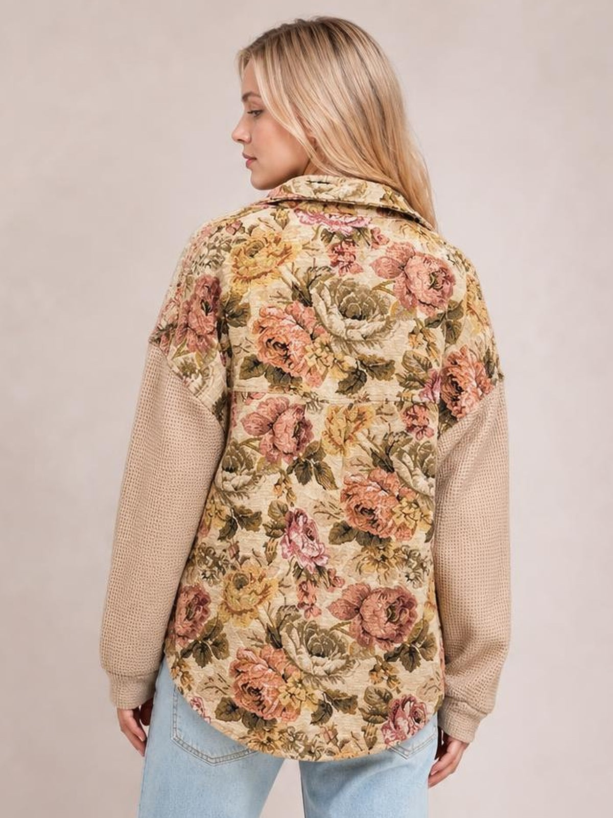 Model shown from behind wearing a relaxed floral patchwork jacket with a cream waffle-knit texture, contrasting sleeves, pointed collar, and curved hem.