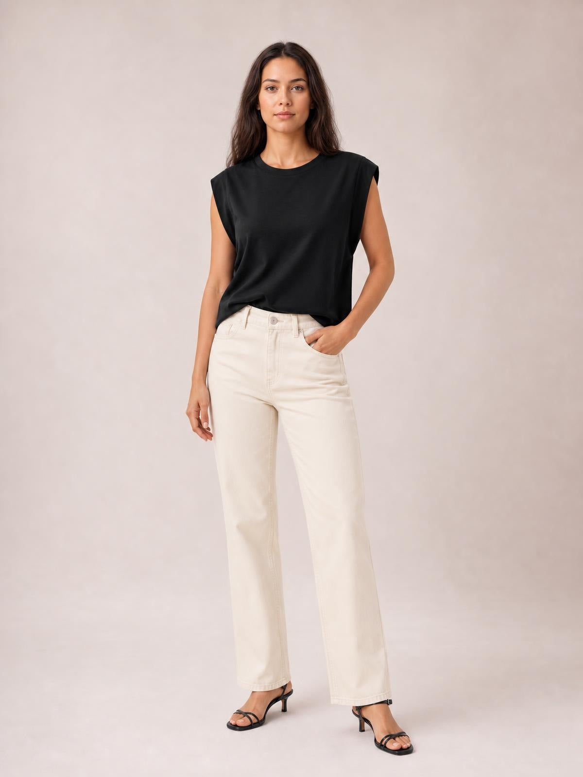 A model stands with one hand in her pocket wearing a black Florira round neck cap sleeve T-shirt with a relaxed, slightly loose silhouette.