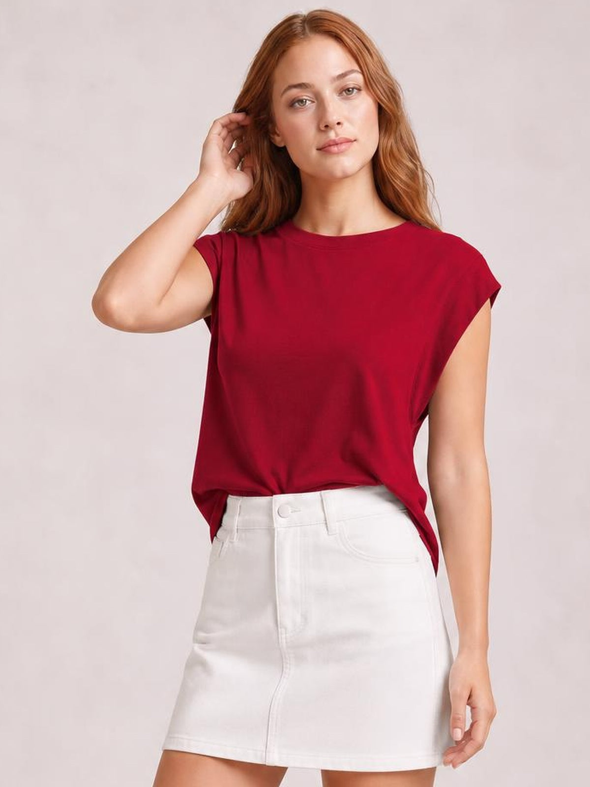 A model wears a deep red Florira round neck cap sleeve T-shirt with a relaxed silhouette, slight front tuck, and smooth opaque construction.