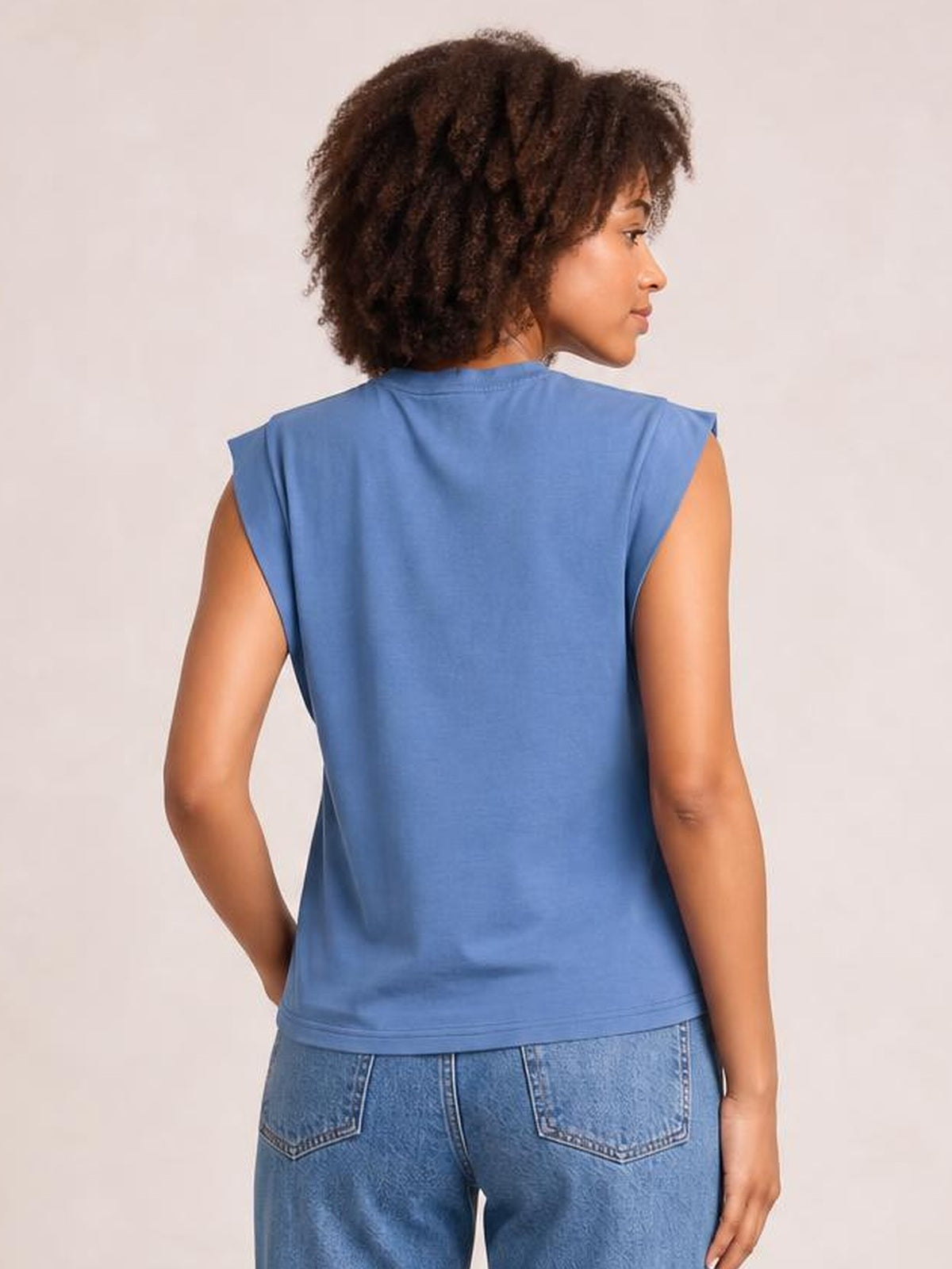 Model in a blue Florira round neck cap sleeve T-shirt, shown from behind with a relaxed straight silhouette and neatly finished hem.