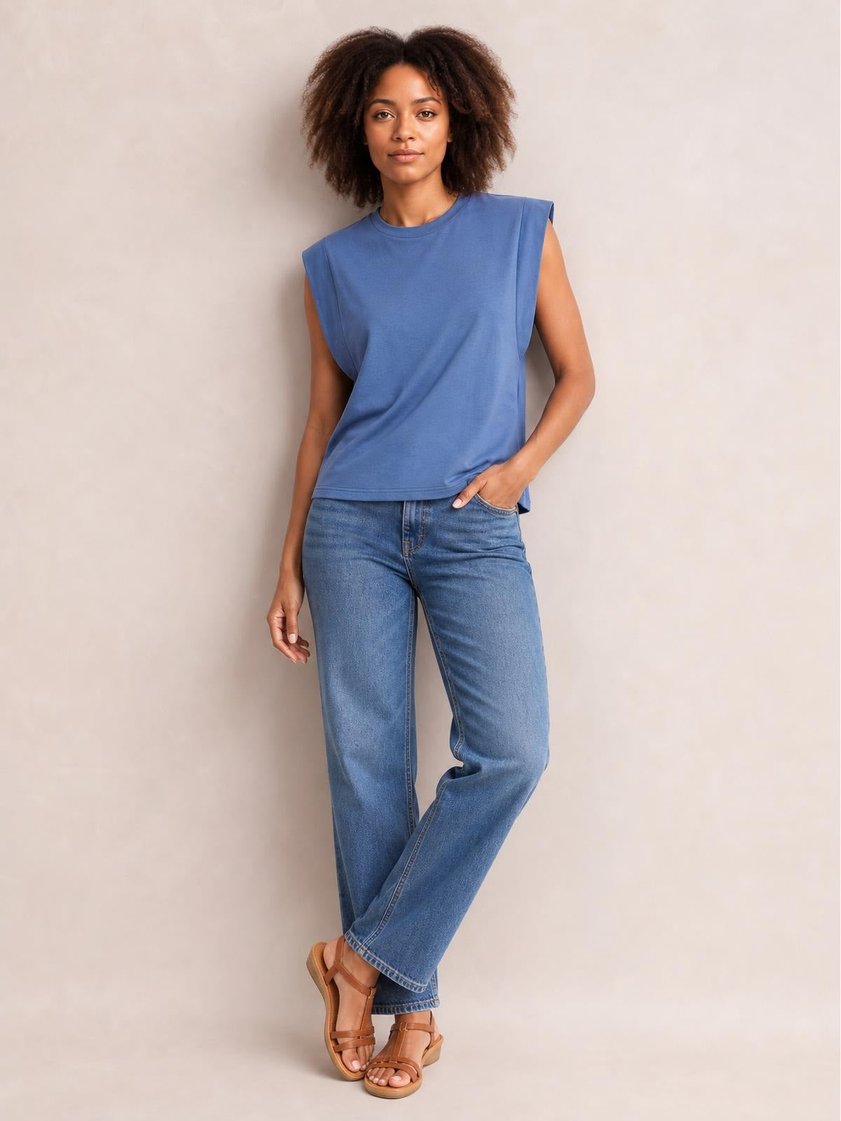 Model wearing a blue Florira round neck cap sleeve T-shirt with a relaxed straight silhouette and clean basic construction, posed with one hand in her jeans pocket.