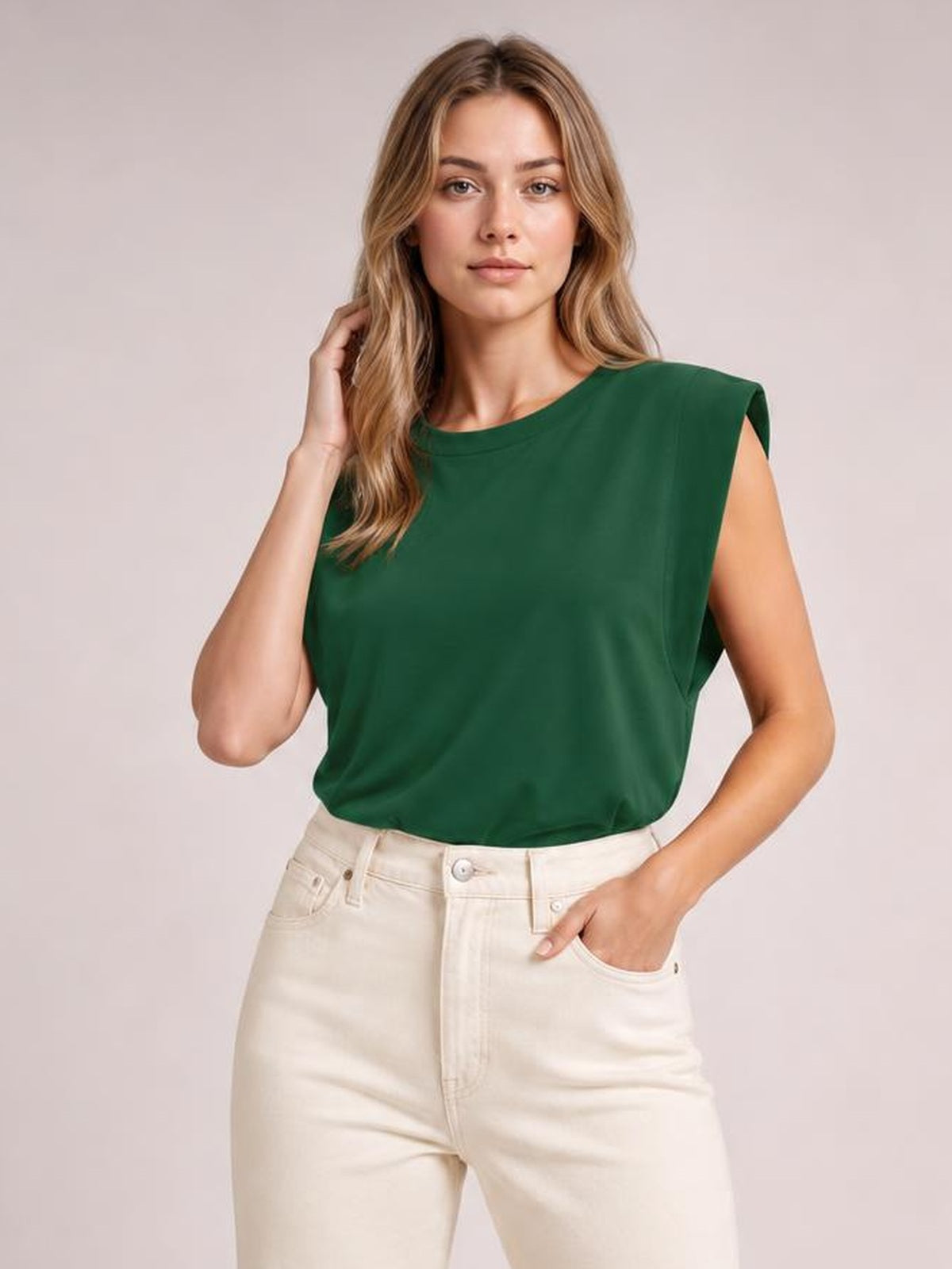 Model wearing a forest green Florira round neck cap sleeve T-shirt with a relaxed silhouette and smooth construction, posing with one hand in her jeans pocket.