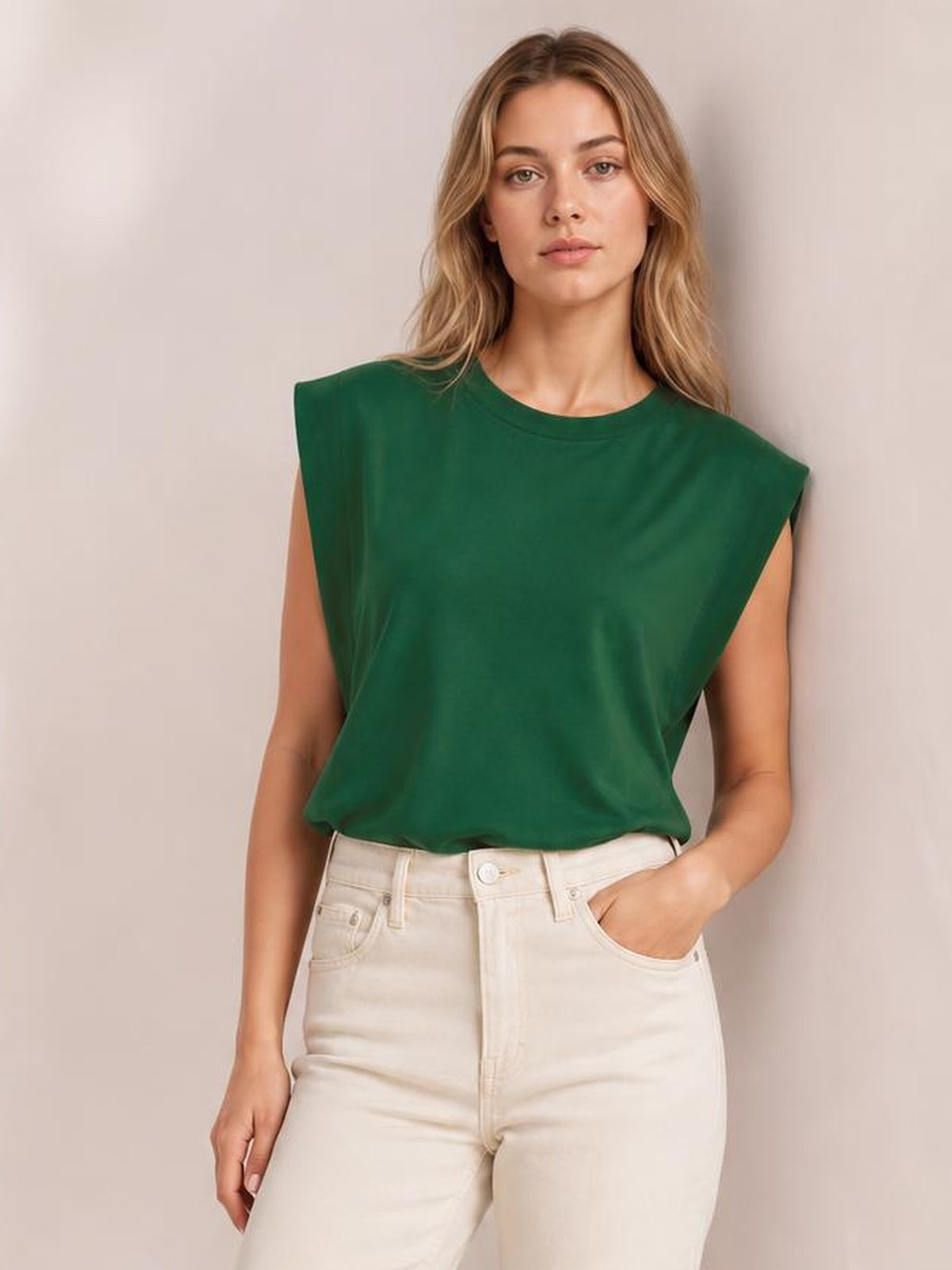 A model wears a forest green Florira round neck cap sleeve T-shirt with a relaxed silhouette, slightly tucked into cream jeans, one hand in a pocket.