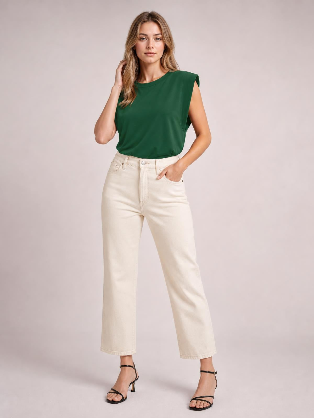 A woman poses in a dark green Florira round neck cap sleeve T-shirt with a relaxed silhouette and slightly cropped hem, one hand resting in her pocket.