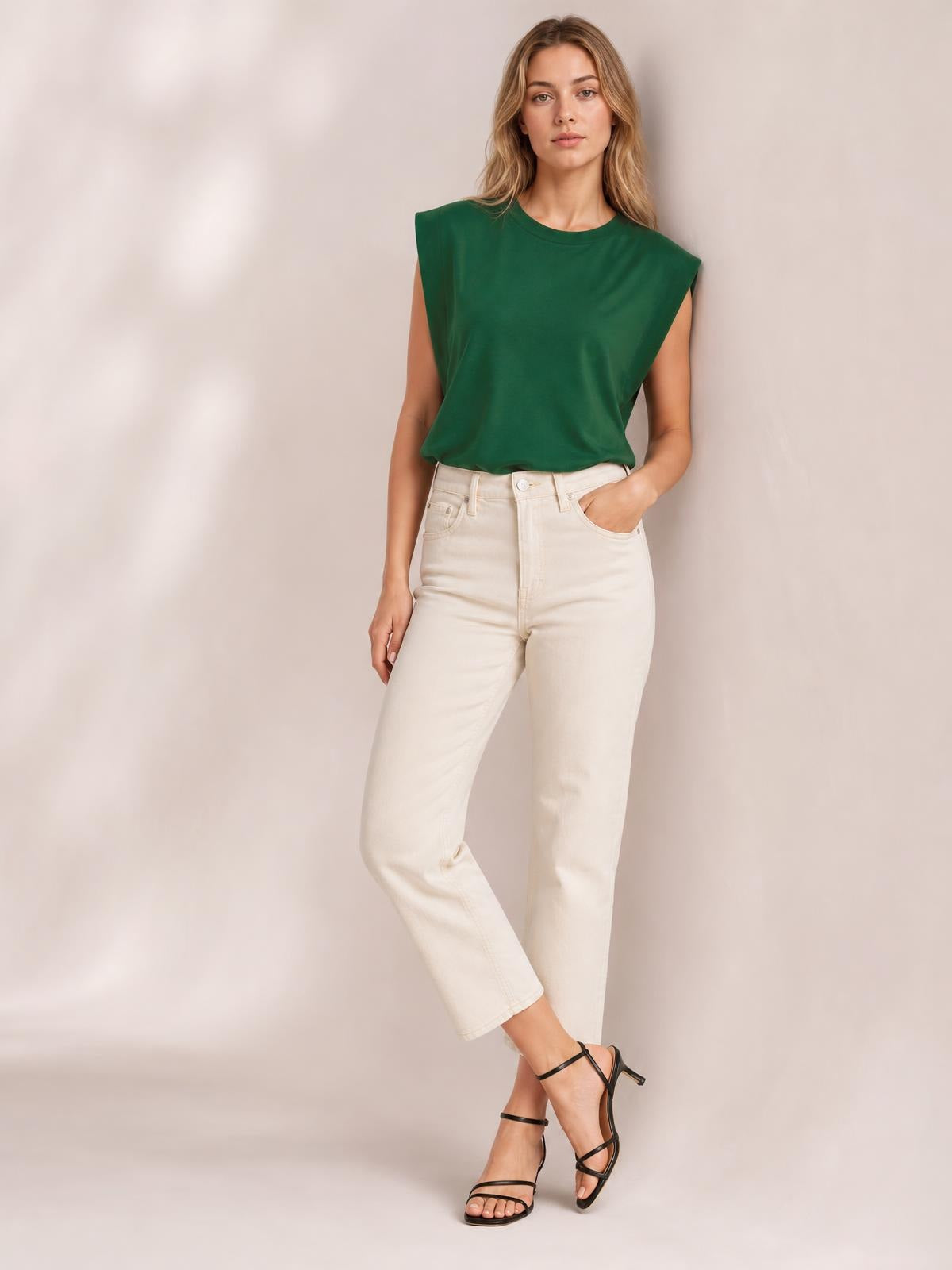 Model wears a green Florira round neck cap sleeve T-shirt with a relaxed silhouette, standing with one hand in her pocket and legs crossed.