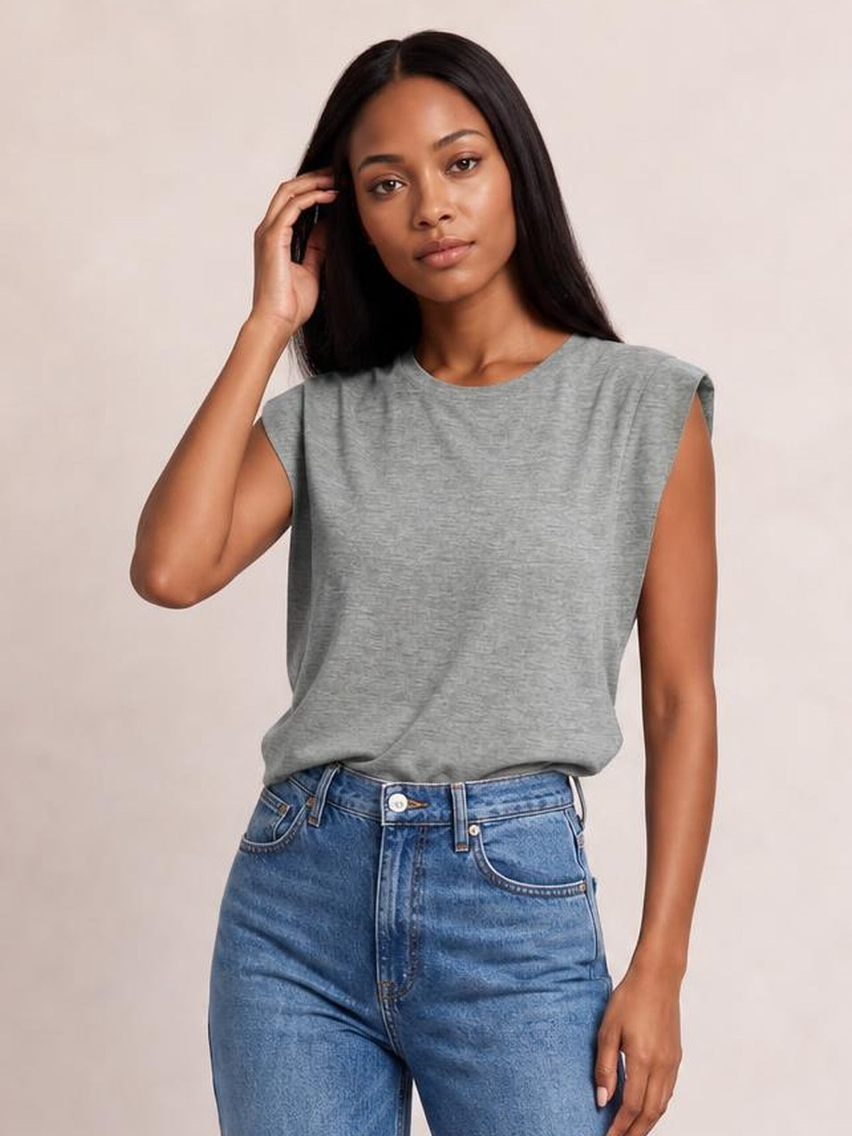 Model wears a gray Florira round neck cap sleeve T-shirt with a relaxed silhouette, slightly dropped shoulders, and a soft drape while touching her hair.