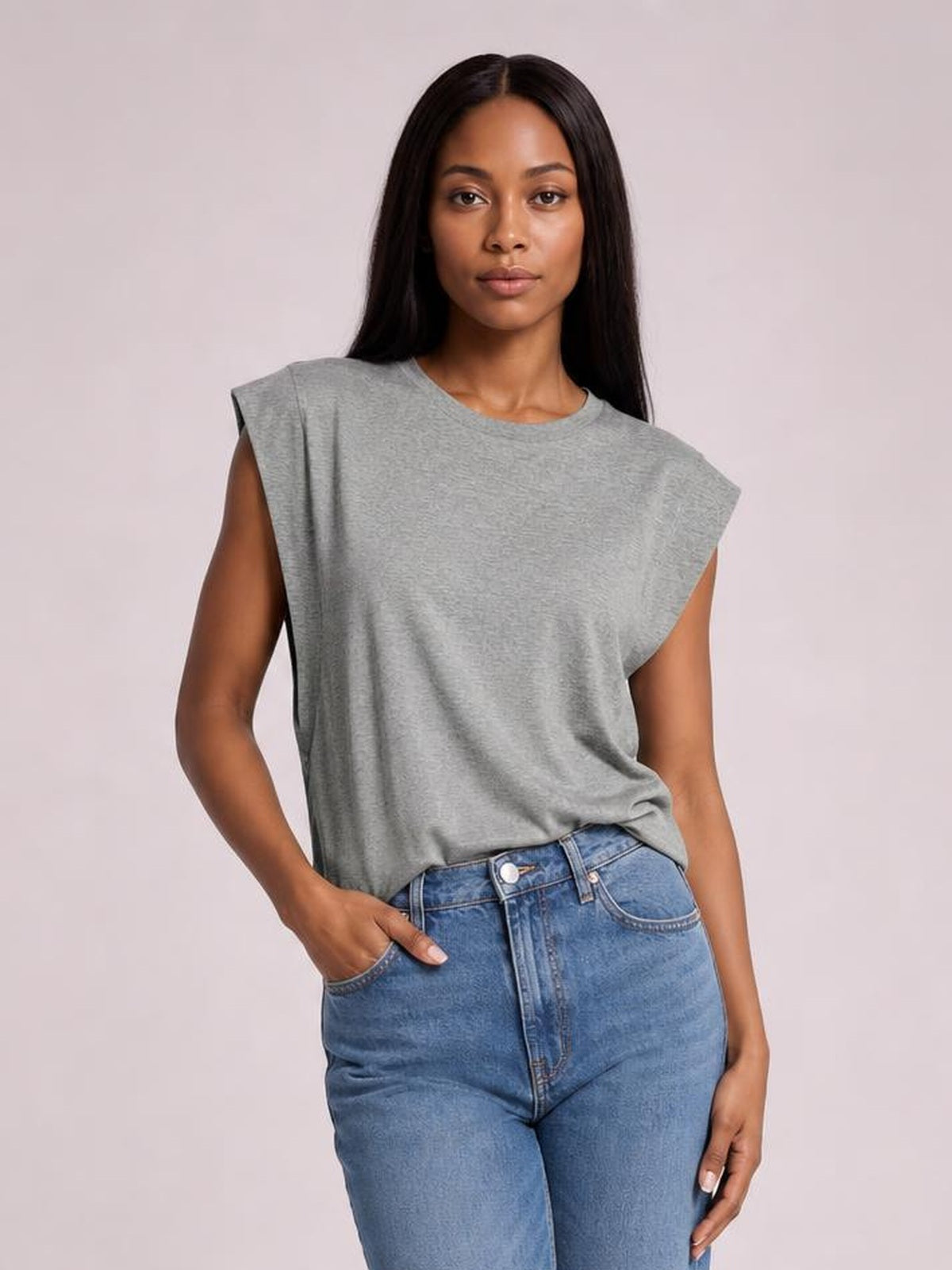 A model poses in a gray Florira round neck cap sleeve T-shirt with a relaxed silhouette, lightly tucked into jeans and one hand in a pocket.