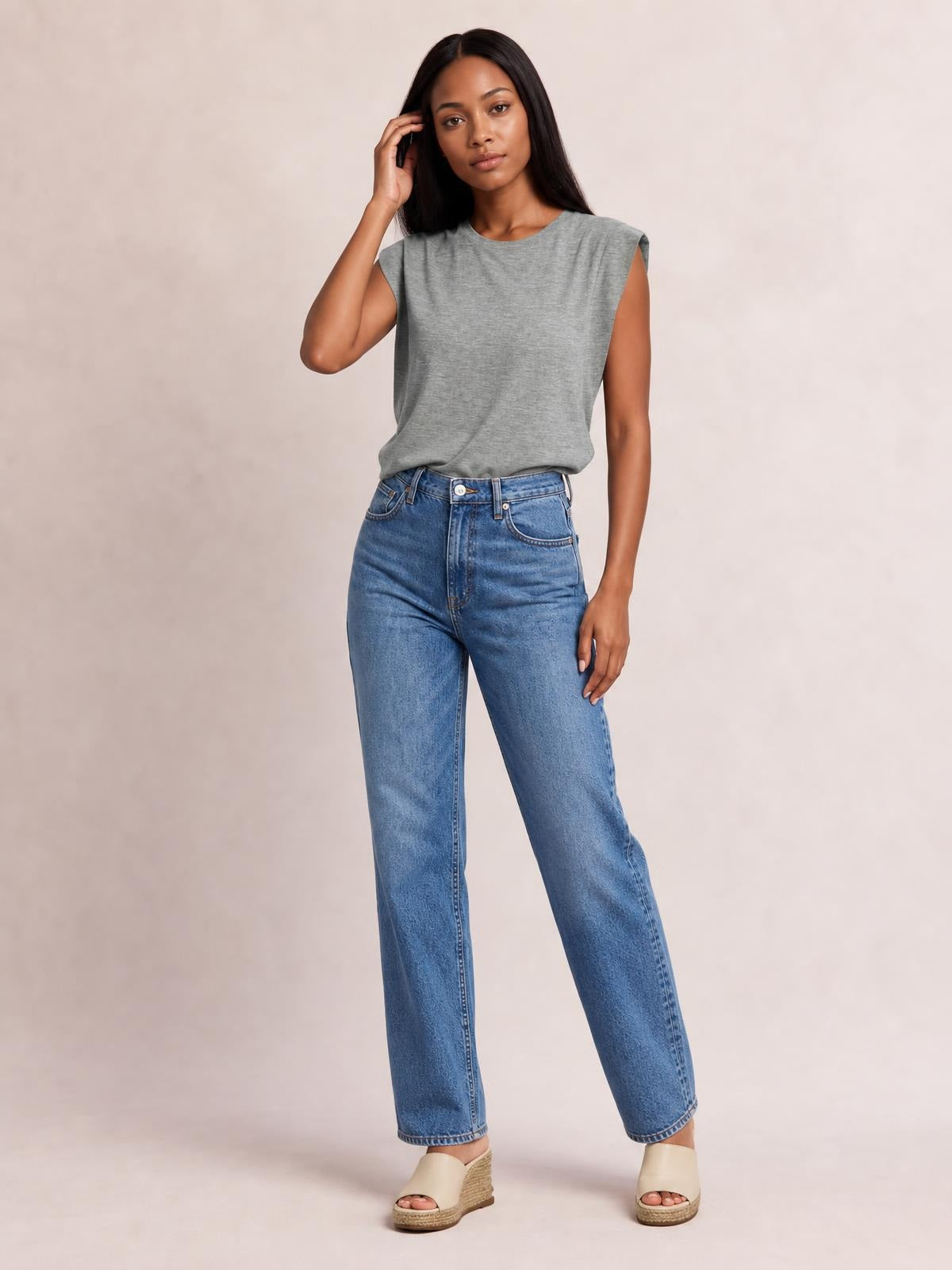 Model wears a gray Florira round neck cap sleeve T-shirt with a relaxed silhouette, slightly tucked into jeans while touching her hair.