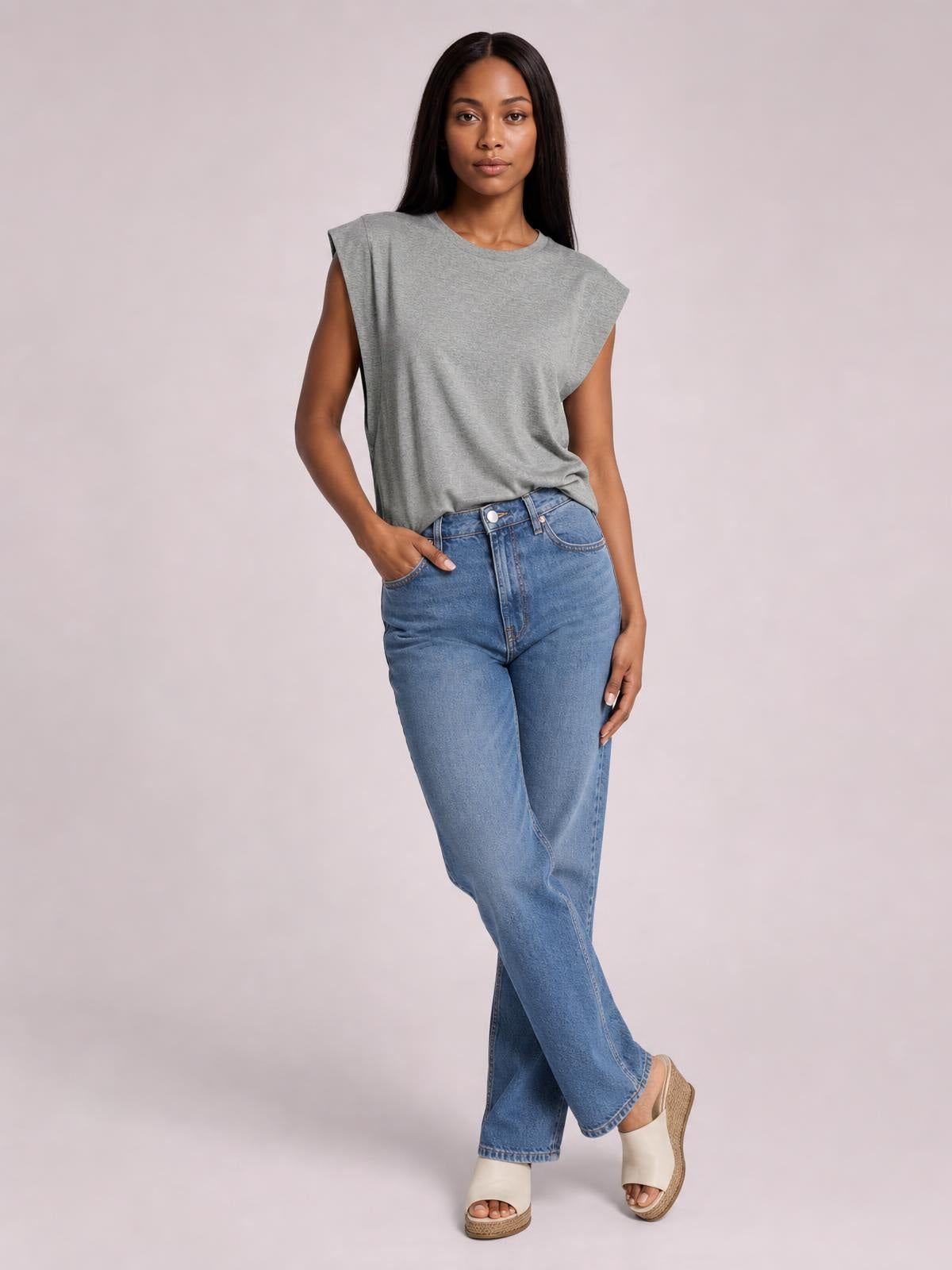 A model wears the gray Florira round-neck cap-sleeve T-shirt in a relaxed silhouette with blue jeans, standing with one hand in a pocket.