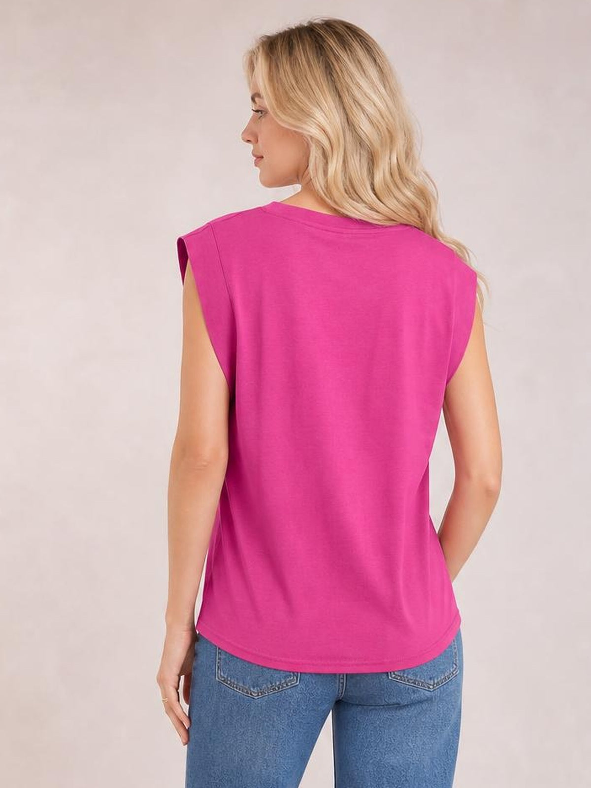 A model poses in a bright pink Florira round neck cap sleeve T-shirt, showing its relaxed silhouette, smooth construction, and gently curved hem from the back.