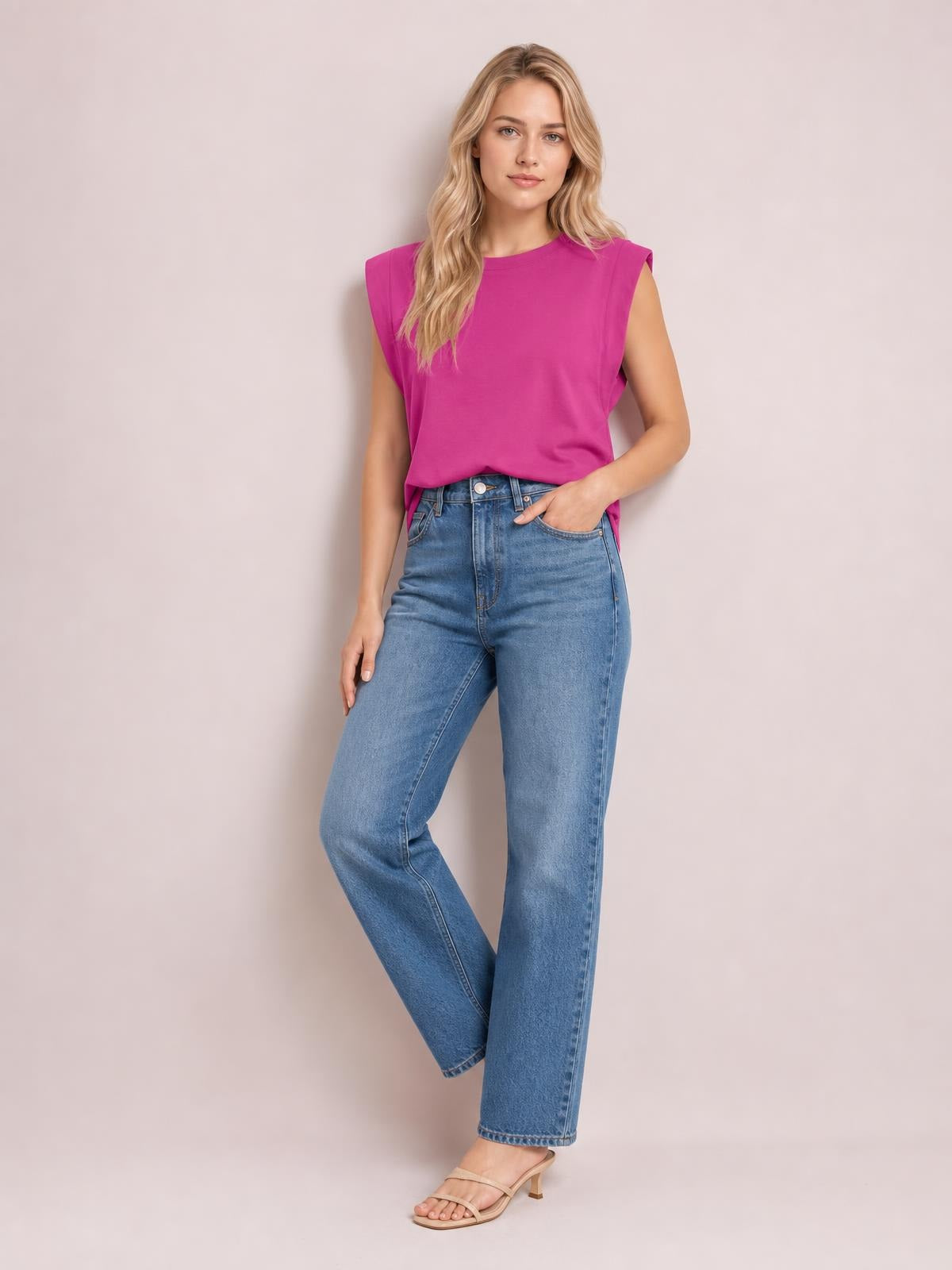 Model poses in a bright fuchsia Florira round neck cap sleeve T-shirt with a relaxed straight silhouette, tucked into jeans and one hand in a pocket.