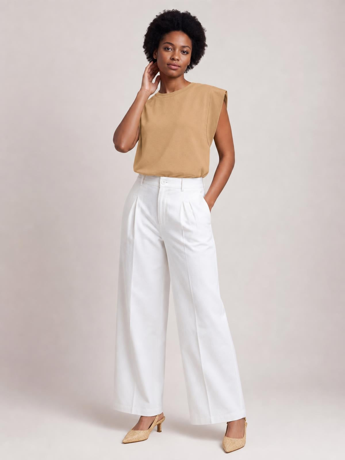 Model wears a tan Florira round neck cap sleeve T-shirt with a relaxed straight silhouette, gently structured shoulders, and one hand resting at her neck.